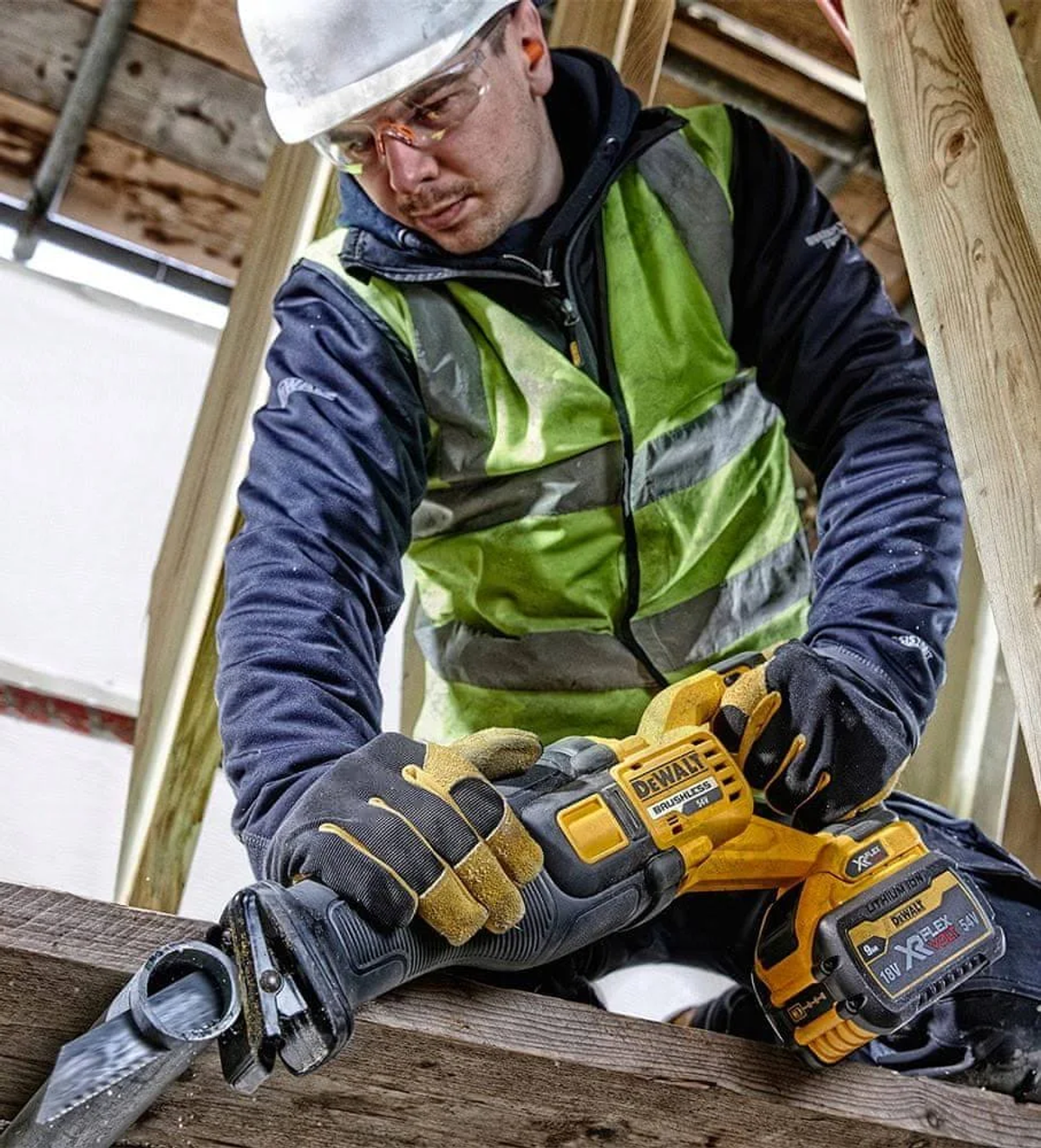 Un trabajador de la construcción usando una sierra recíproca DeWalt para cortar una tubería, con equipo de seguridad.