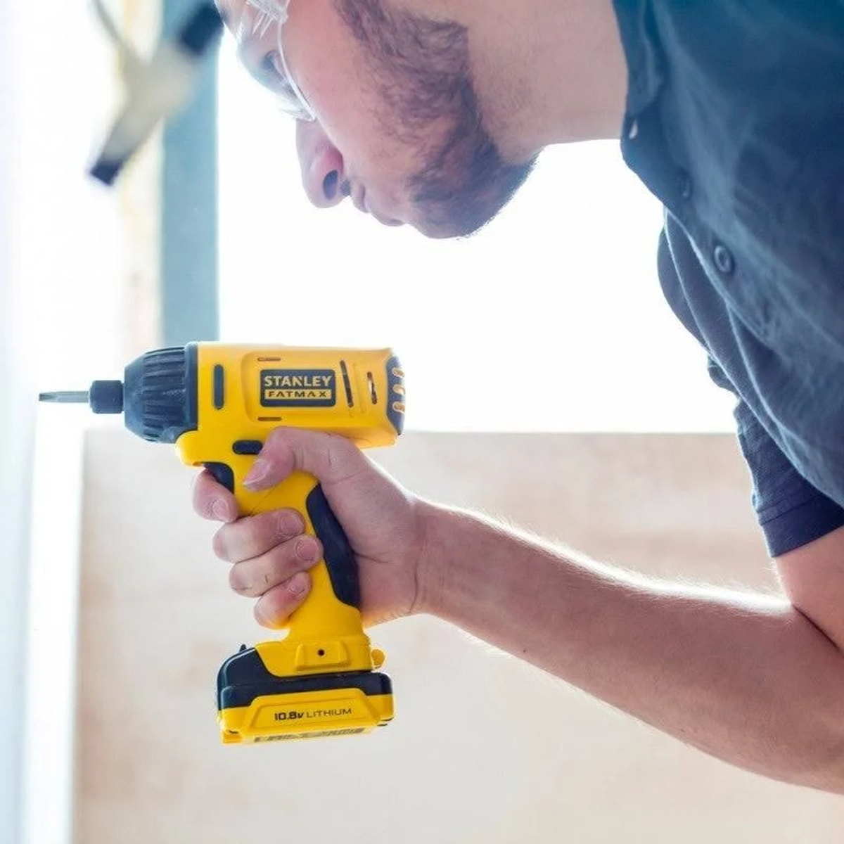 Una persona che utilizza un avvitatore a impulsi Stanley Fatmax giallo.