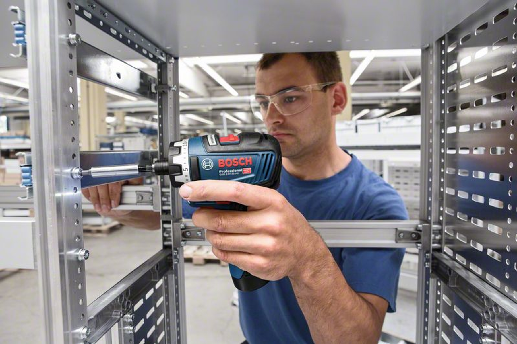 Mężczyzna w okularach używa śrubokręta Bosch. Ma na sobie niebieską koszulę.