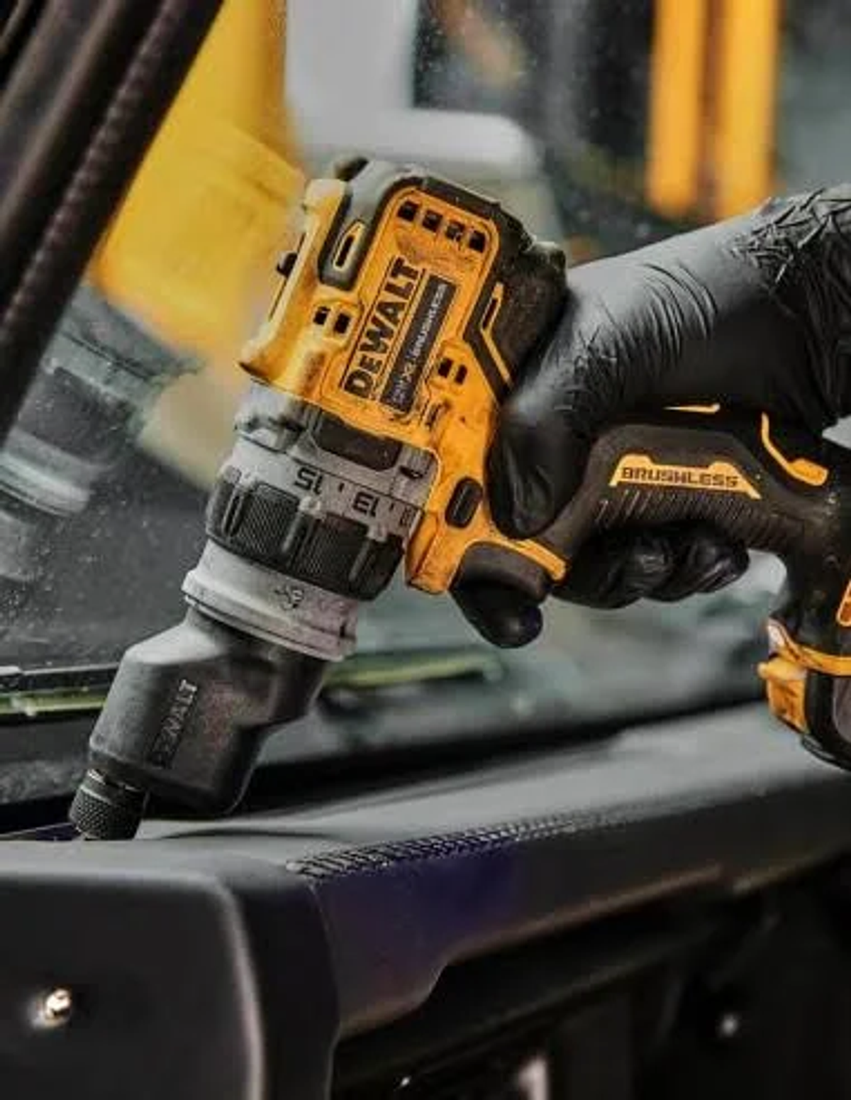 Una mano con guante negro usando un taladro Dewalt amarillo y negro sobre una superficie negra.