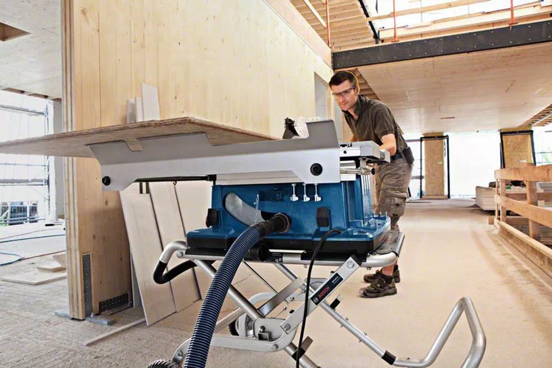 Un uomo usa una sega da tavolo blu. La sega è su un supporto, in un cantiere.