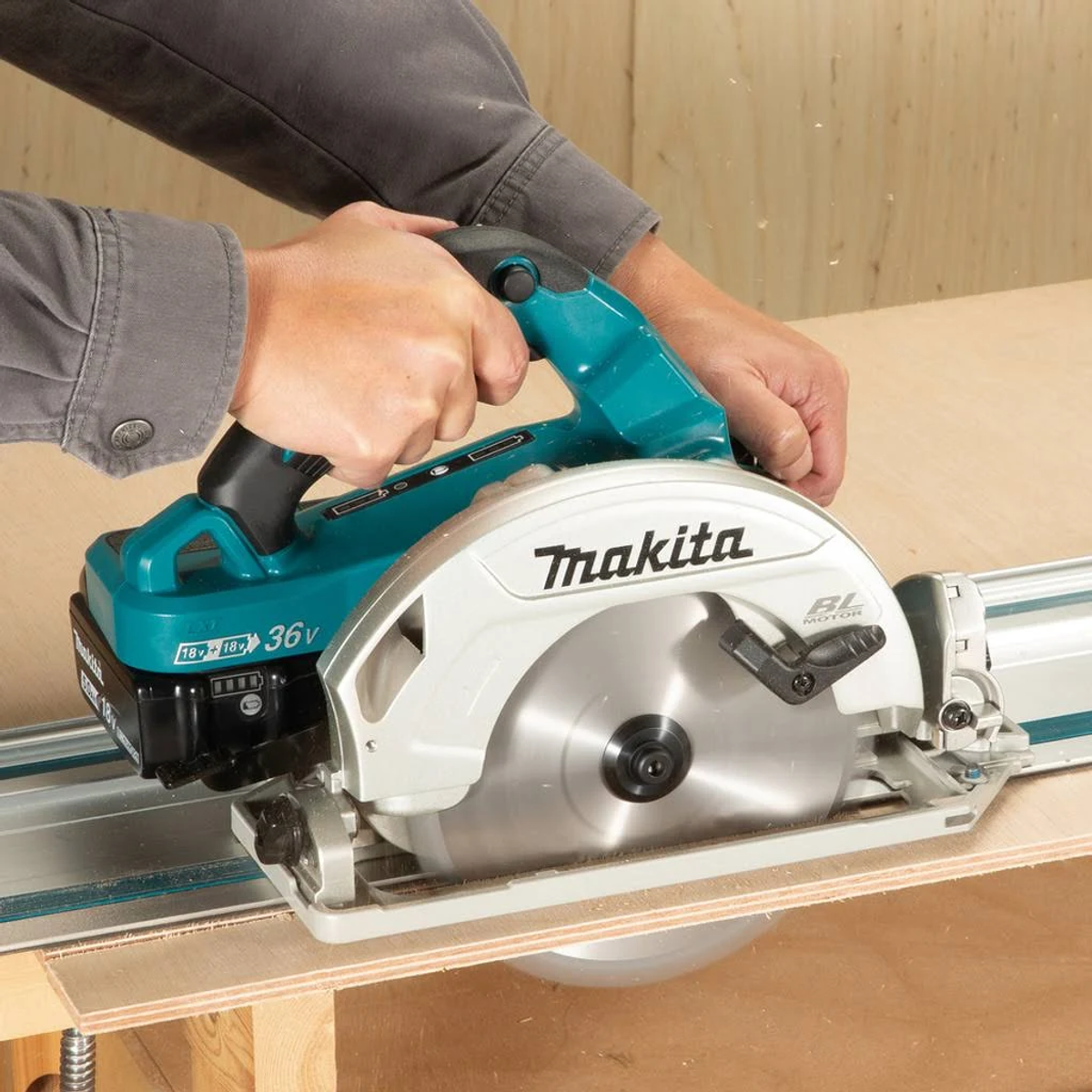 Person schneidet mit einer Makita Kreissäge ein Stück Holz. Türkis und weiße Farben.