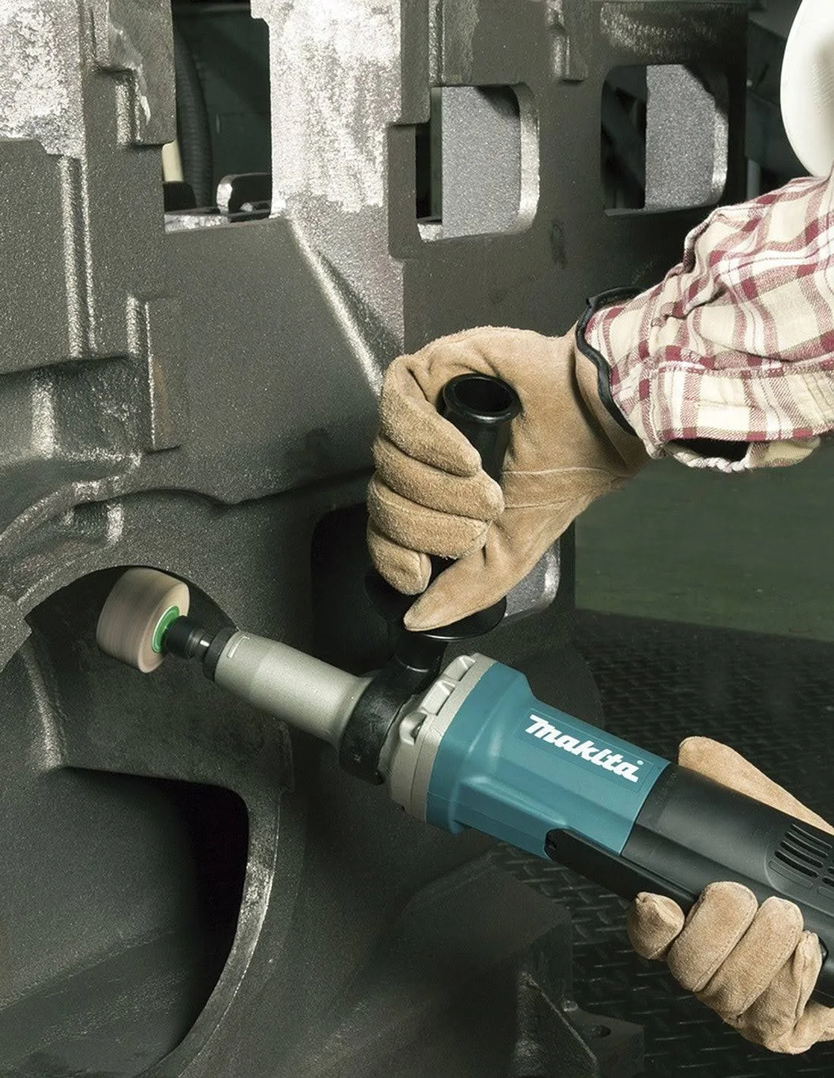 Una persona usando una amoladora angular Makita con una muela en una superficie metálica, usando guantes.