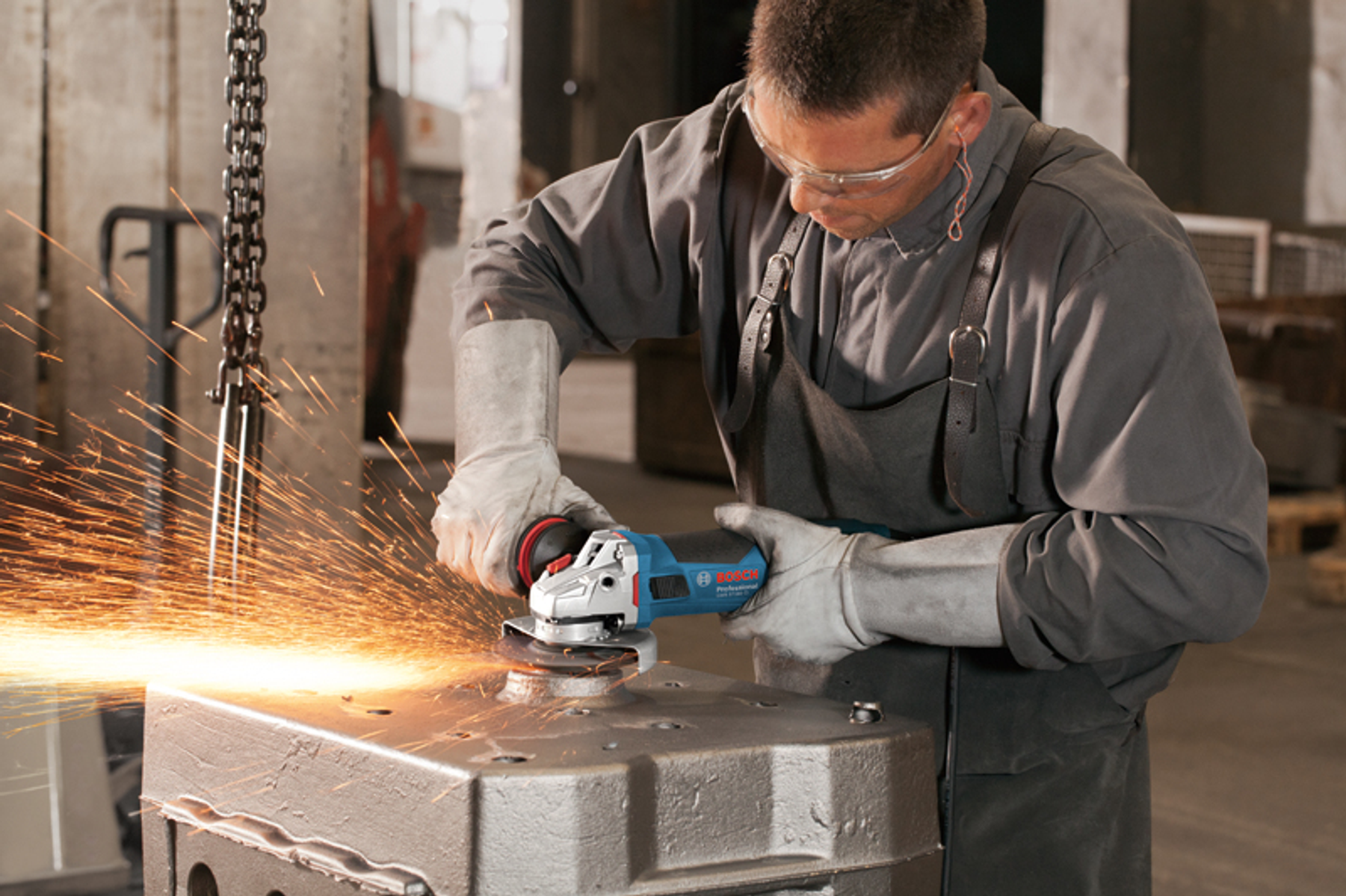 Un hombre moliendo metal con una amoladora angular Bosch, chispas volando en un taller.