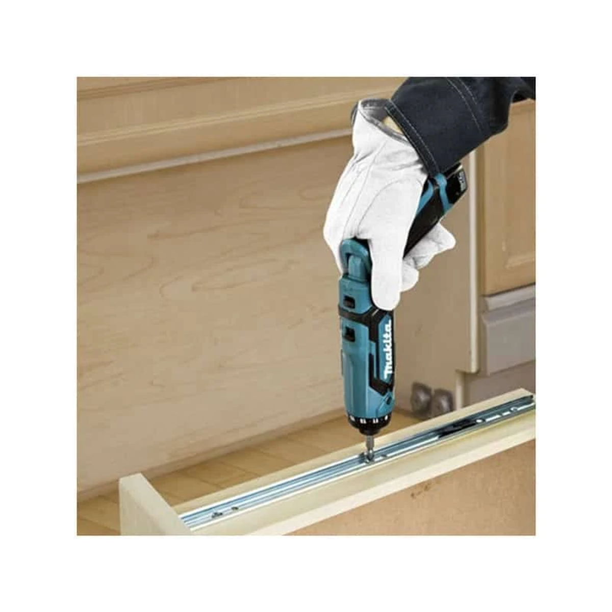 Ręka w rękawicy używająca wkrętarki akumulatorowej Makita w kolorze morskim, na drewnianej powierzchni.