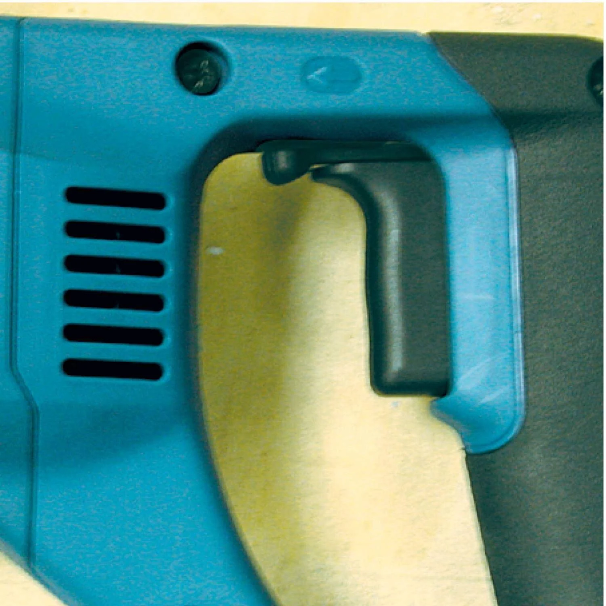 Zbliżenie na niebieski uchwyt elektronarzędzia z otworami wentylacyjnymi.