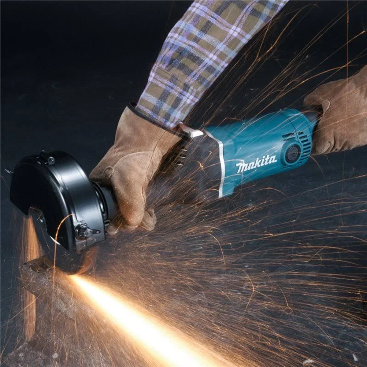 Persona usando una amoladora angular Makita, cortando metal con chispas.