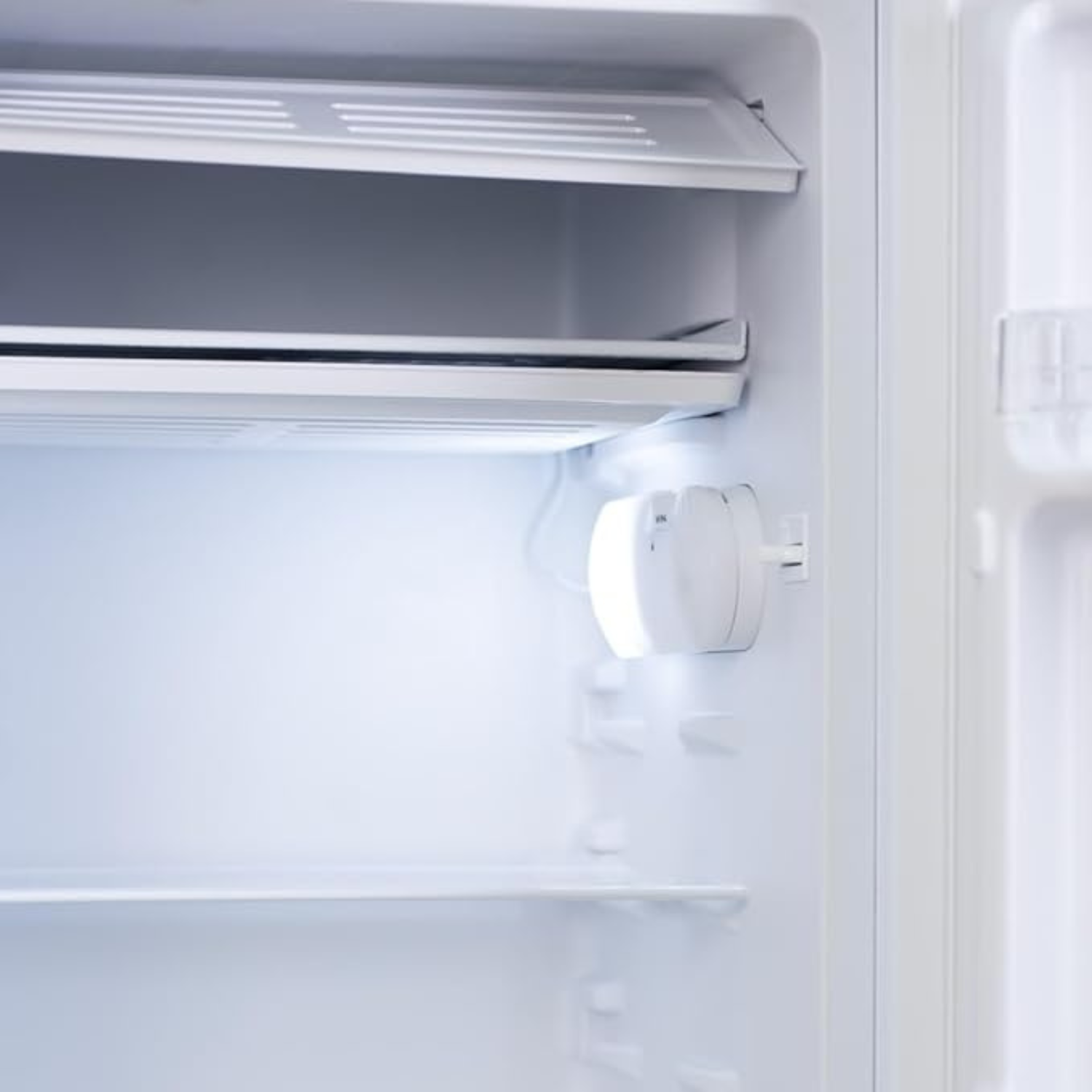 Interno di un frigorifero con ripiani e luce.
