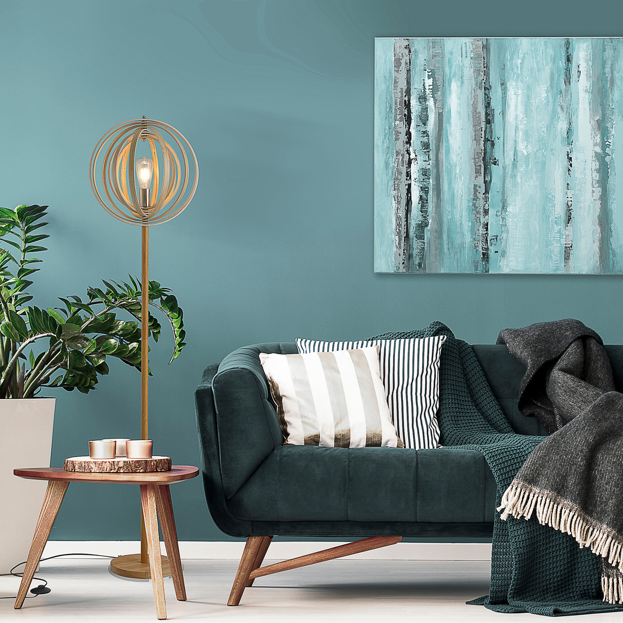 Una lampada dorata accanto a un divano verde scuro. Un dipinto appeso al muro blu.