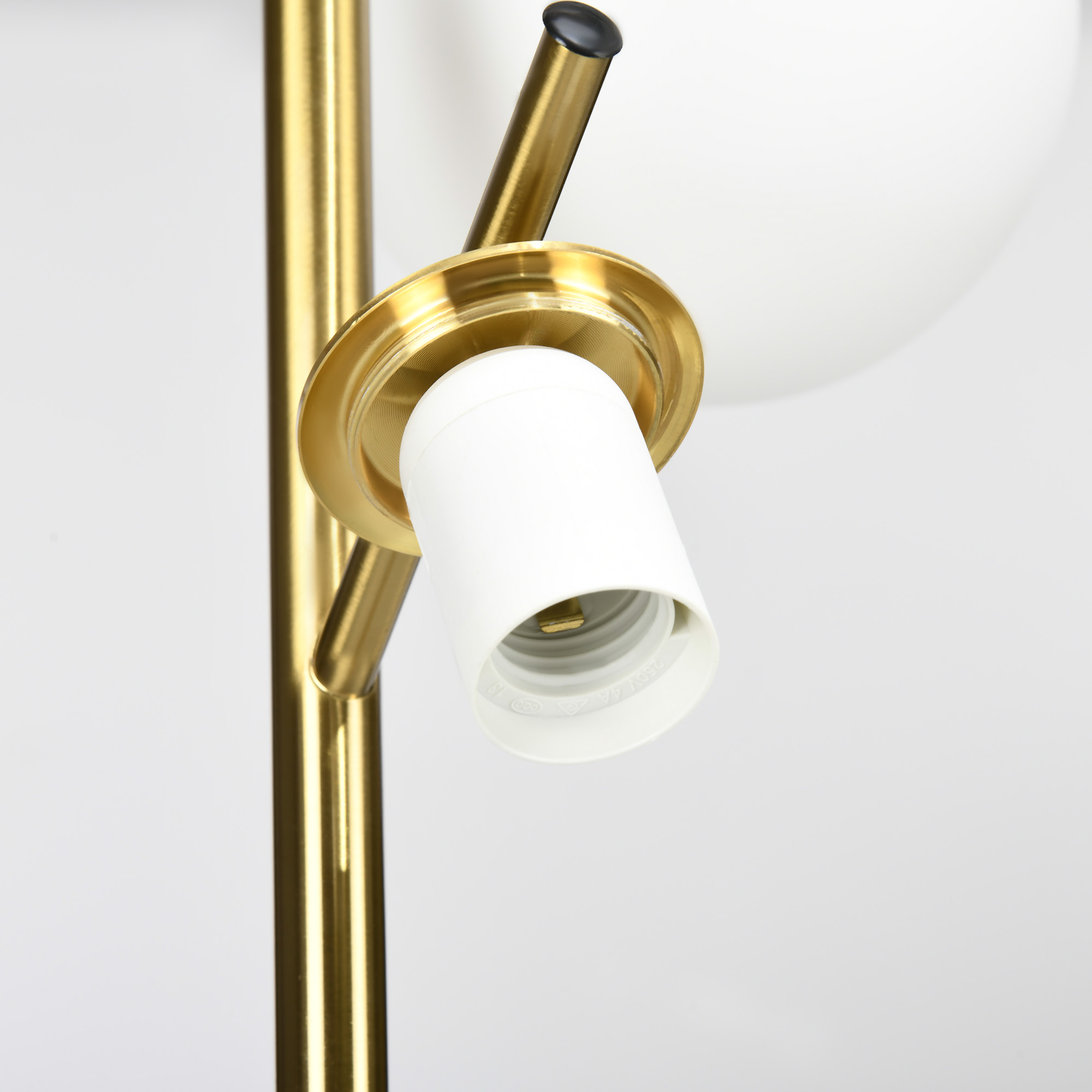 Primo piano di una lampada dorata e in ottone. La lampada presenta un portalampada e una lampadina bianca.