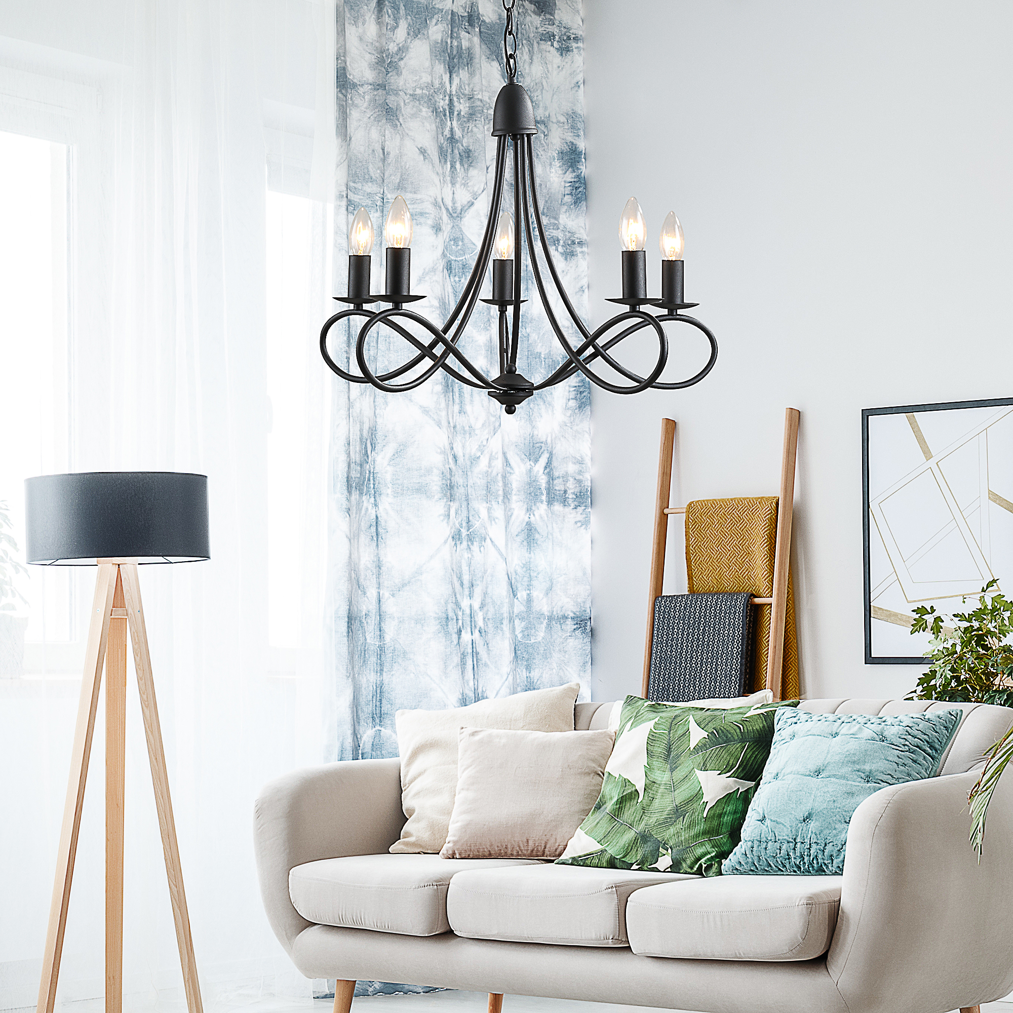 Un lampadario nero con cinque lampadine. Sono visibili un divano e una lampada.