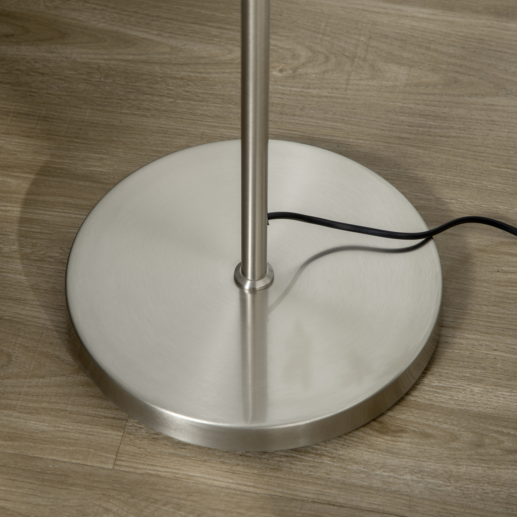 Primo piano della base metallica di una lampada da terra. Un cavo parte dalla base.