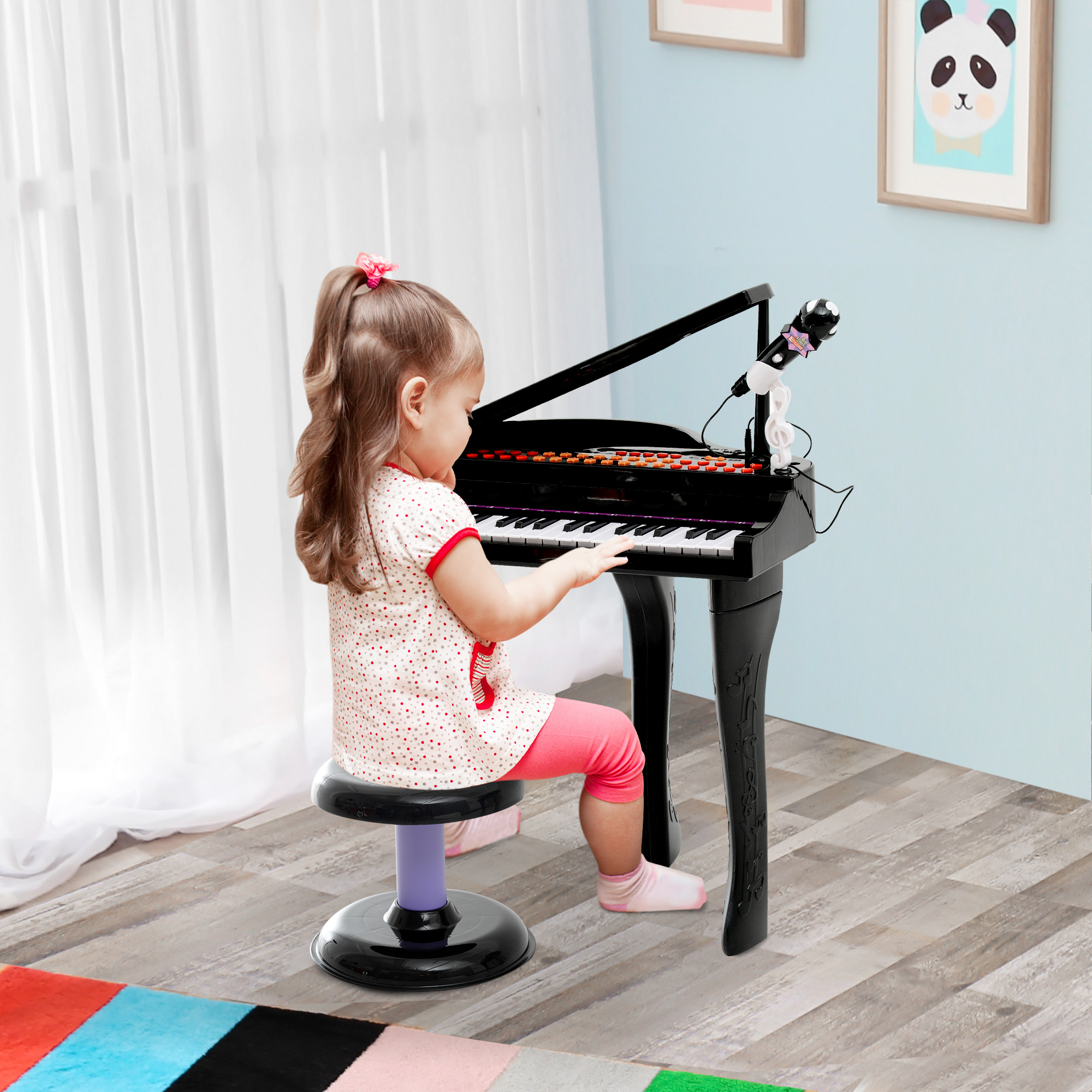 Una niña tocando un piano de juguete. Lleva pantalones rosas y una camiseta roja.