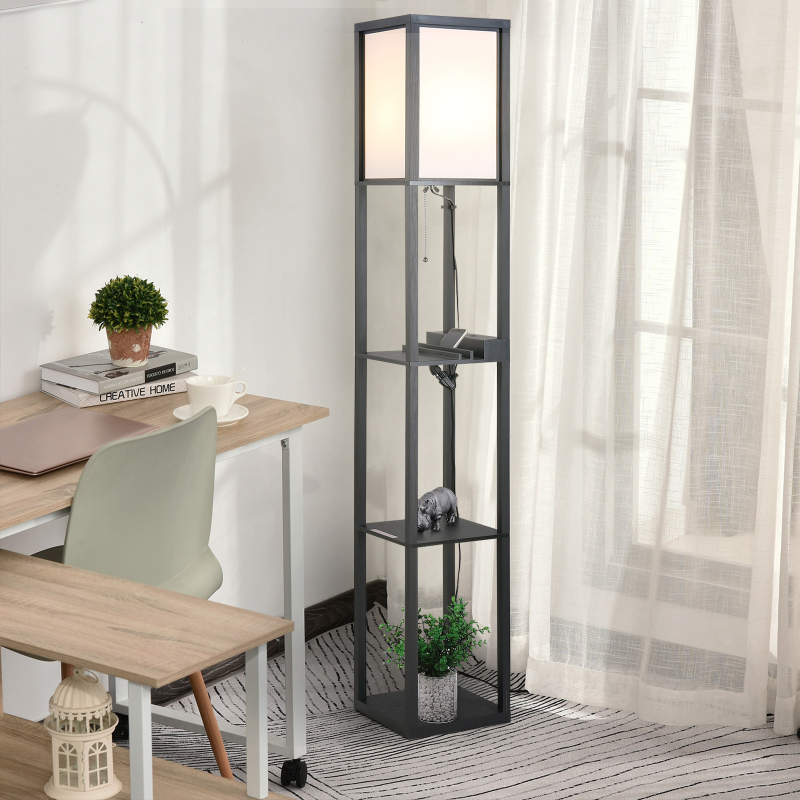 Lampada da terra nera con ripiani, accanto a una scrivania e una finestra con tende.