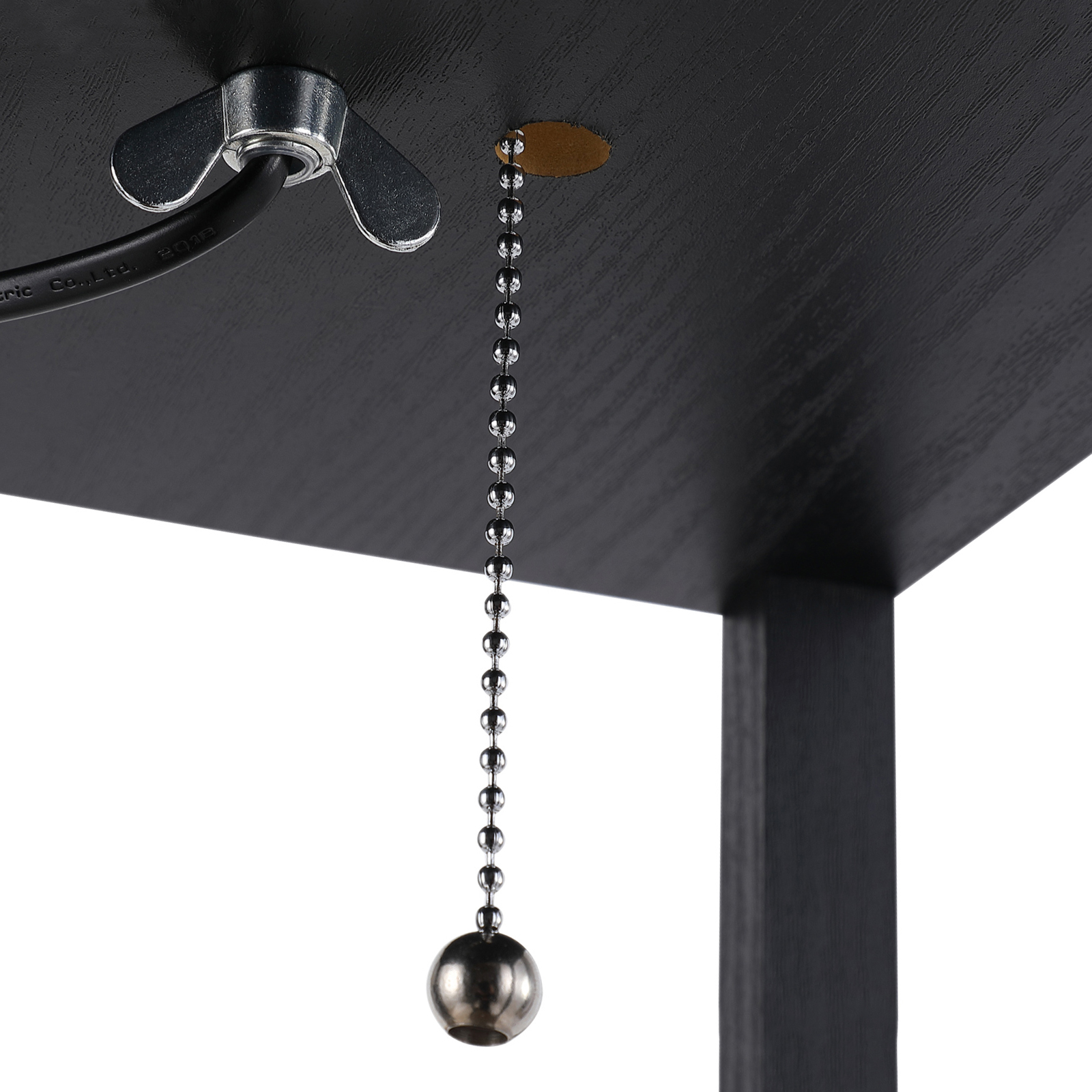 Primo piano di una superficie nera con una catena di trazione e un galletto metallico. Sfondo bianco.