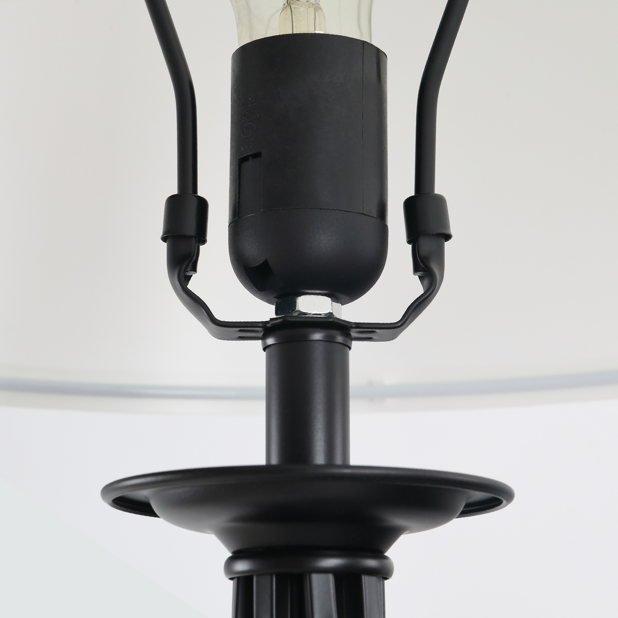 Primo piano della parte superiore di una lampada nera con paralume bianco.
