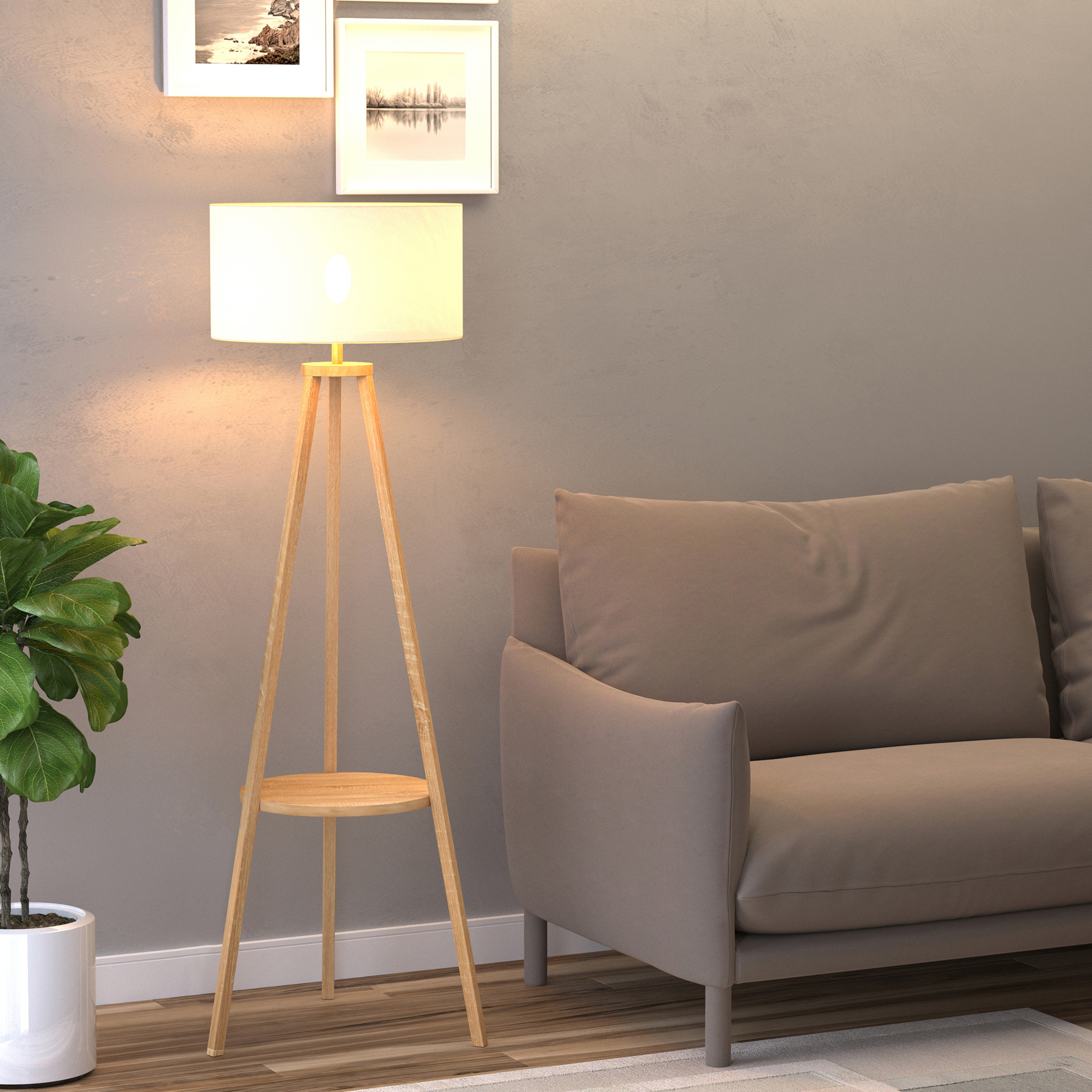 Una lampada da terra a treppiede in legno con paralume bianco. Nella scena ci sono anche una pianta e un divano.