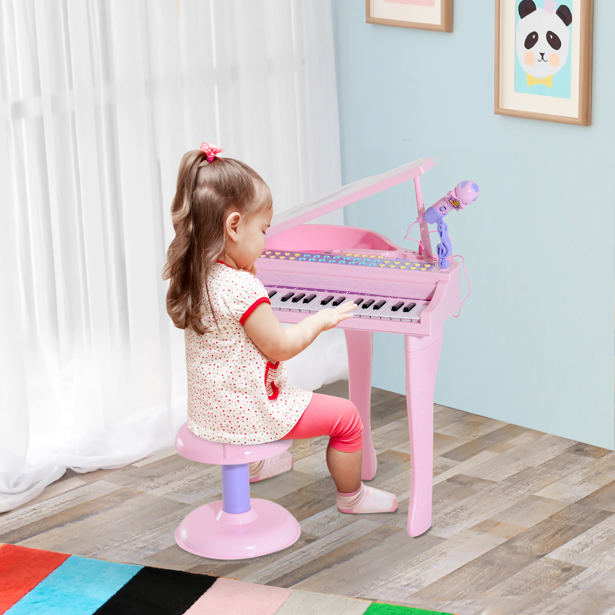 Una bambina che suona un pianoforte rosa. C'è un microfono e uno sgabello. Un tappeto colorato è sul pavimento.
