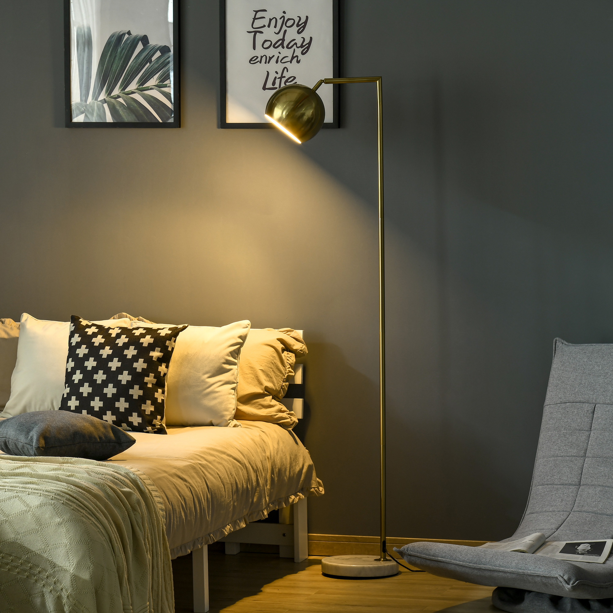 Lampada da terra dorata con paralume rotondo, vicino a un letto, con arte e decorazioni.