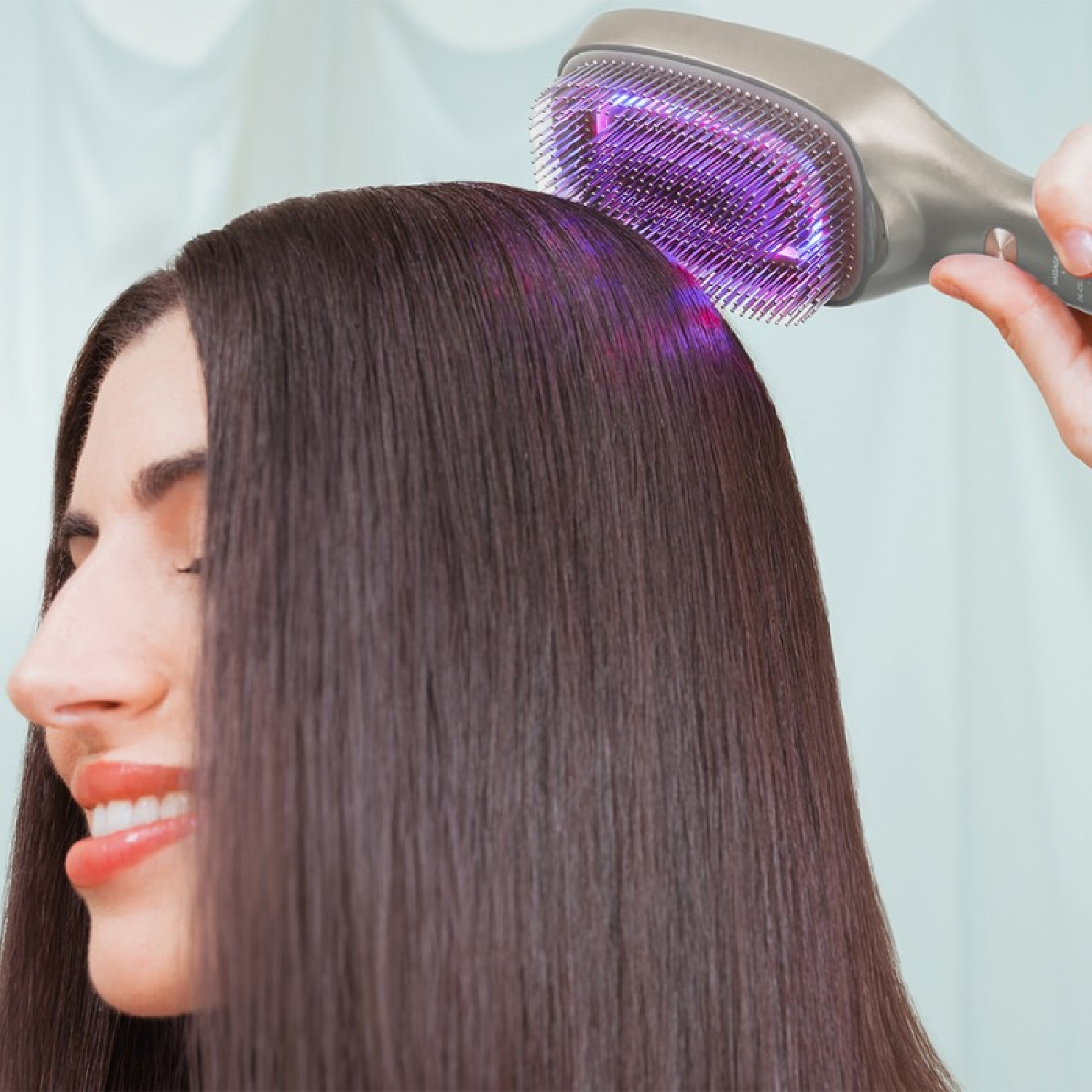 La testa di una donna con capelli scuri viene trattata con un dispositivo per la crescita dei capelli che emette luce viola.