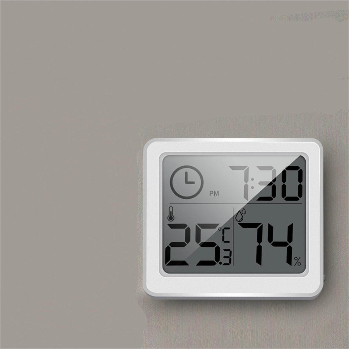Eine Digitaluhr mit Zeit-, Temperatur- und Luftfeuchtigkeitsanzeige vor grauem Hintergrund.