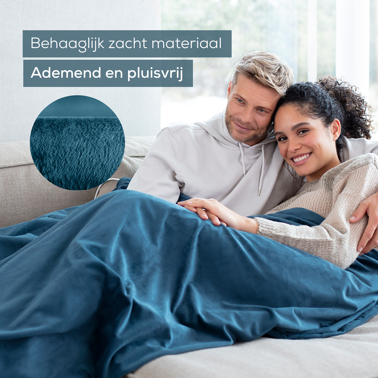 Una coppia avvolta in una coperta blu, con testo sopra. Stanno sorridendo. Sfondo color turchese.