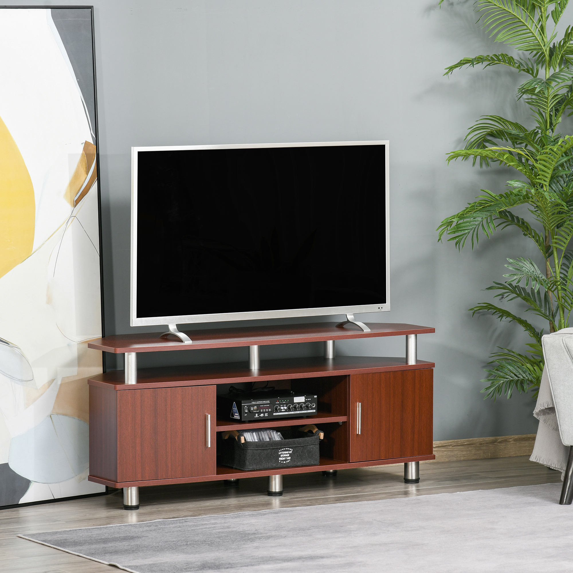 Un mobile TV marrone con TV e ripiani. Una pianta e decorazioni sono nelle vicinanze.