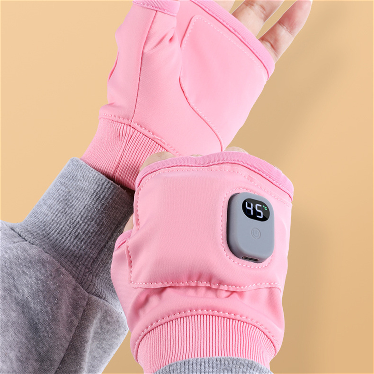 Beheizbare rosa Handschuhe. Die Temperaturanzeige zeigt 45 Grad. Hände sind in die Fingerhandschuhe gesteckt.