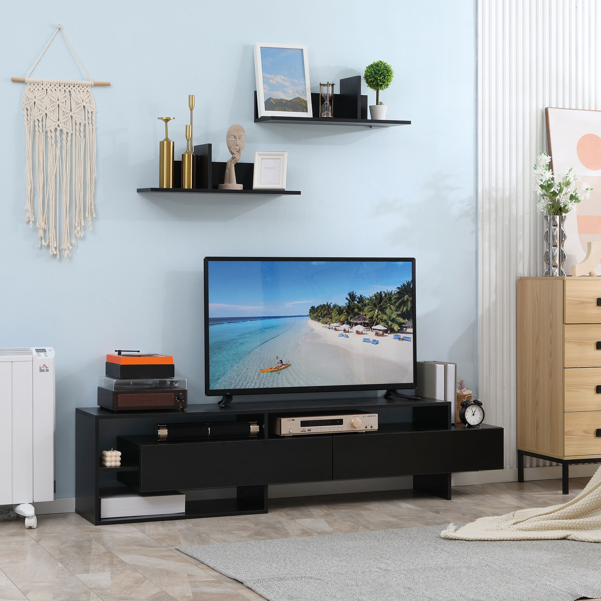 Soggiorno con mobile TV nero, TV, decorazioni murali e parete azzurra.