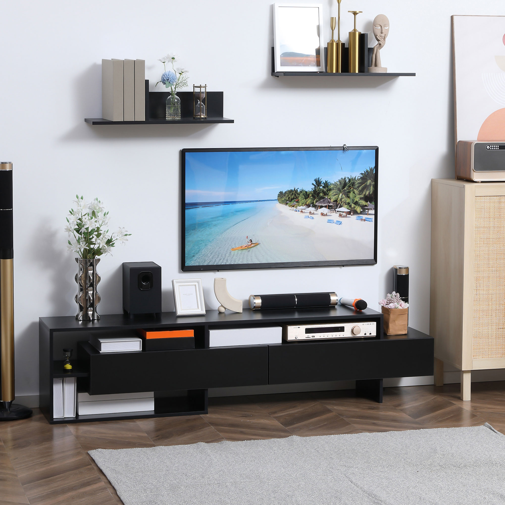 Un mobile TV nero con un televisore che mostra una scena di spiaggia. Mensole e decorazioni sono sulla parete sopra.