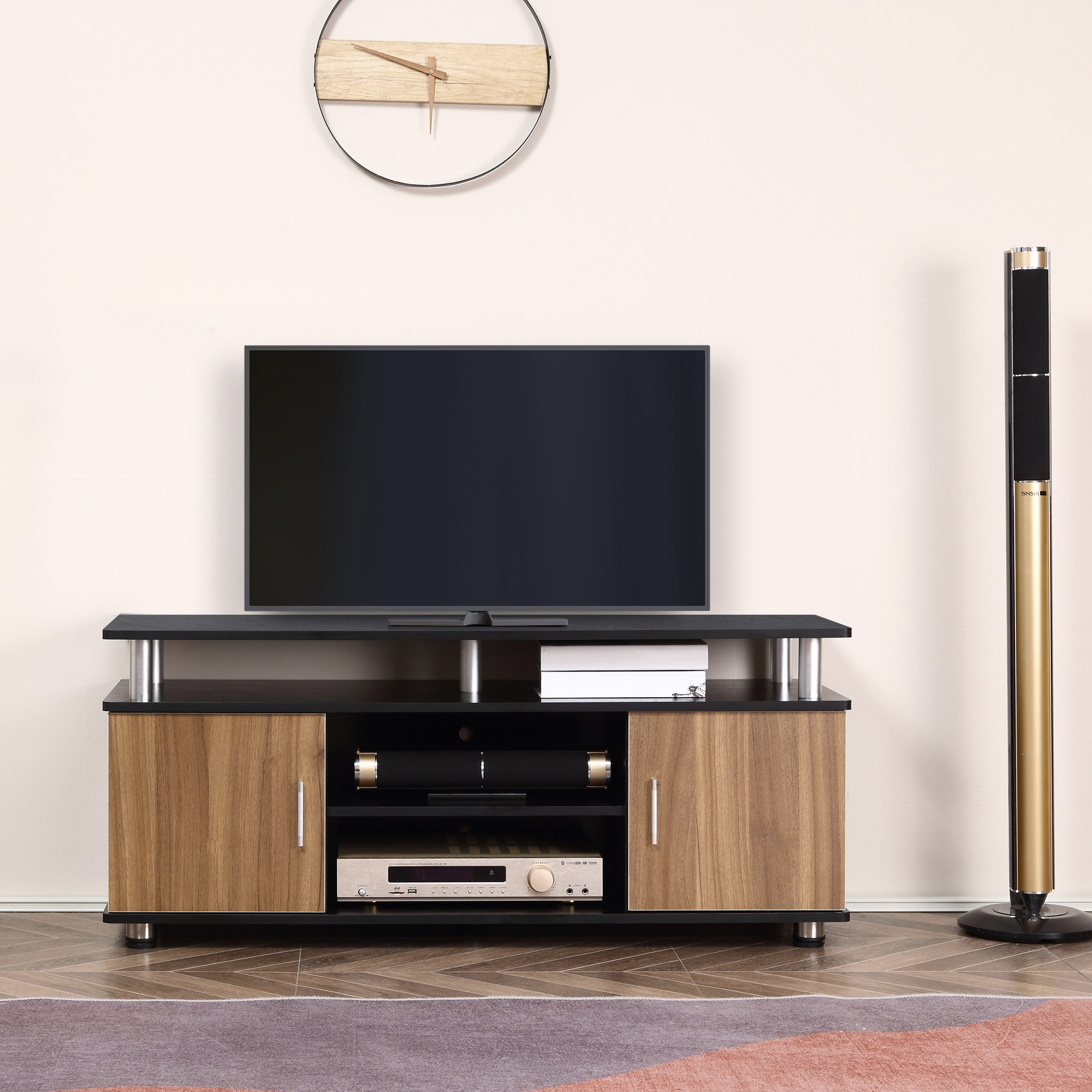 Un televisore su un supporto nero e in legno. Un orologio e un impianto audio sullo sfondo.
