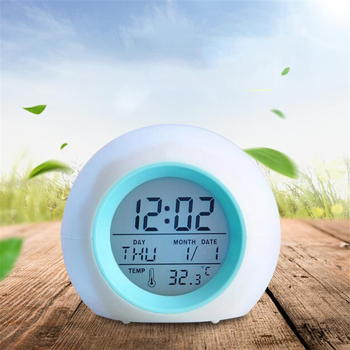 Eine weiß-blaue Digitaluhr, die Zeit und Datum anzeigt. Hintergrund aus Himmel und Holztisch.