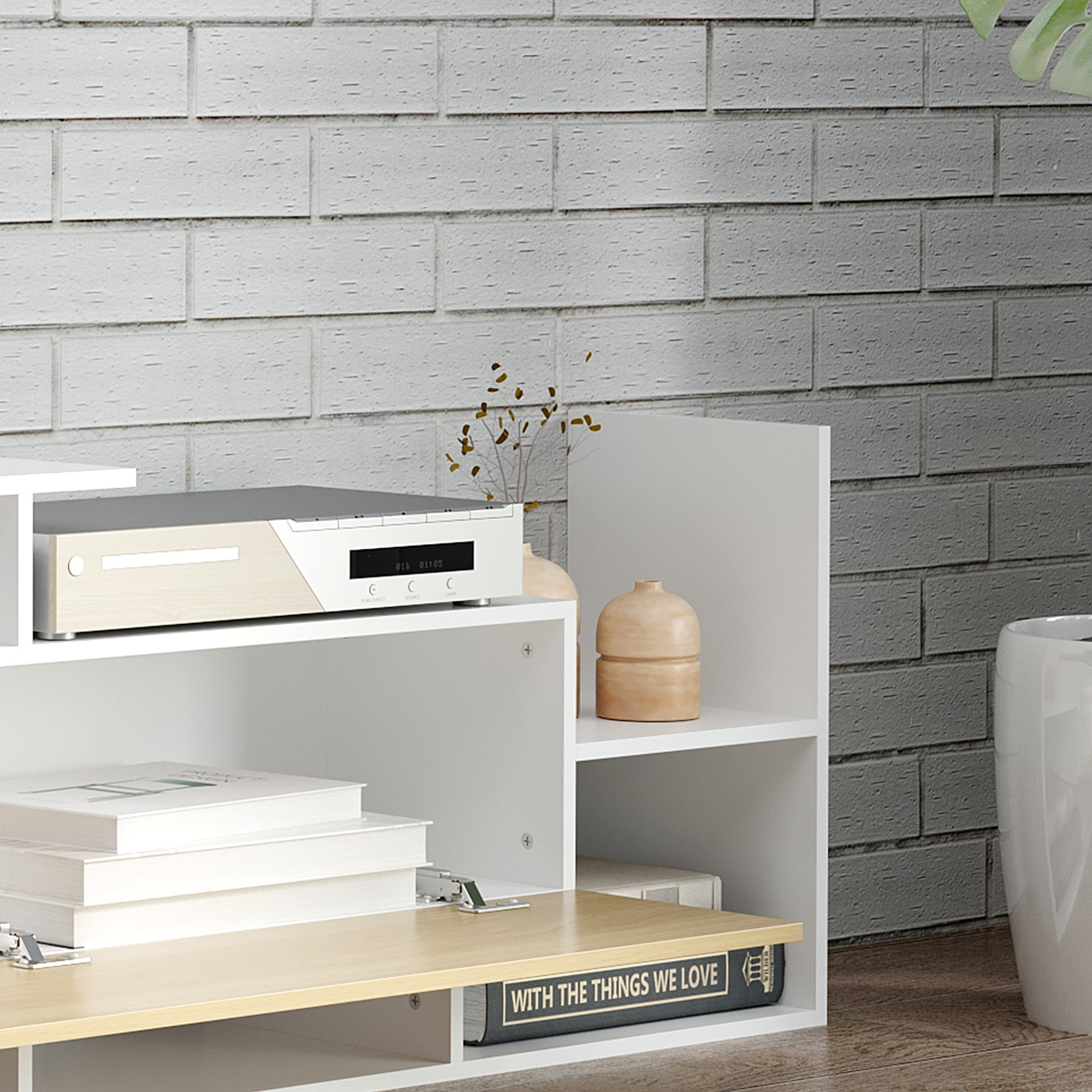 Un mobile TV con lettore DVD, libri e oggetti decorativi contro un muro di mattoni.
