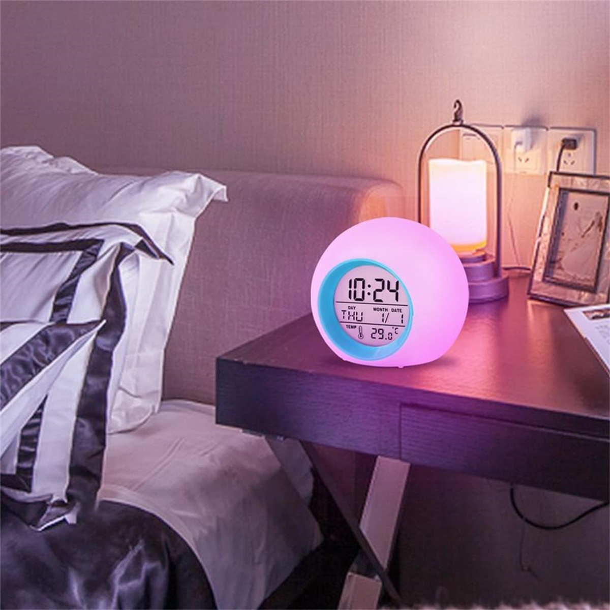 Ein farbwechselnder Wecker auf einem Nachttisch, mit einer Lampe dahinter.