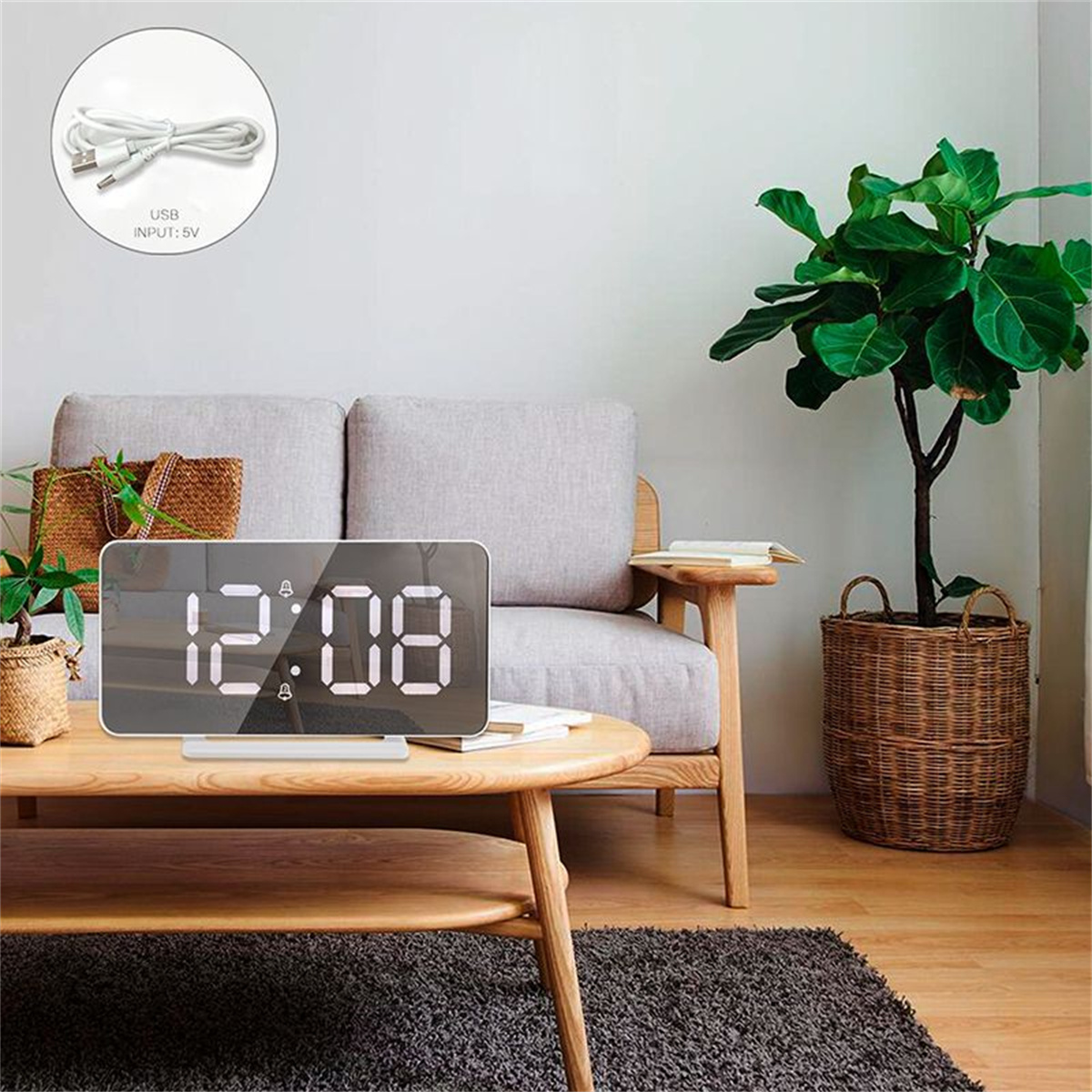 Eine Digitaluhr, die 12:08 anzeigt, mit einem USB-Kabel auf einem Tisch und einer Pflanze im Hintergrund.