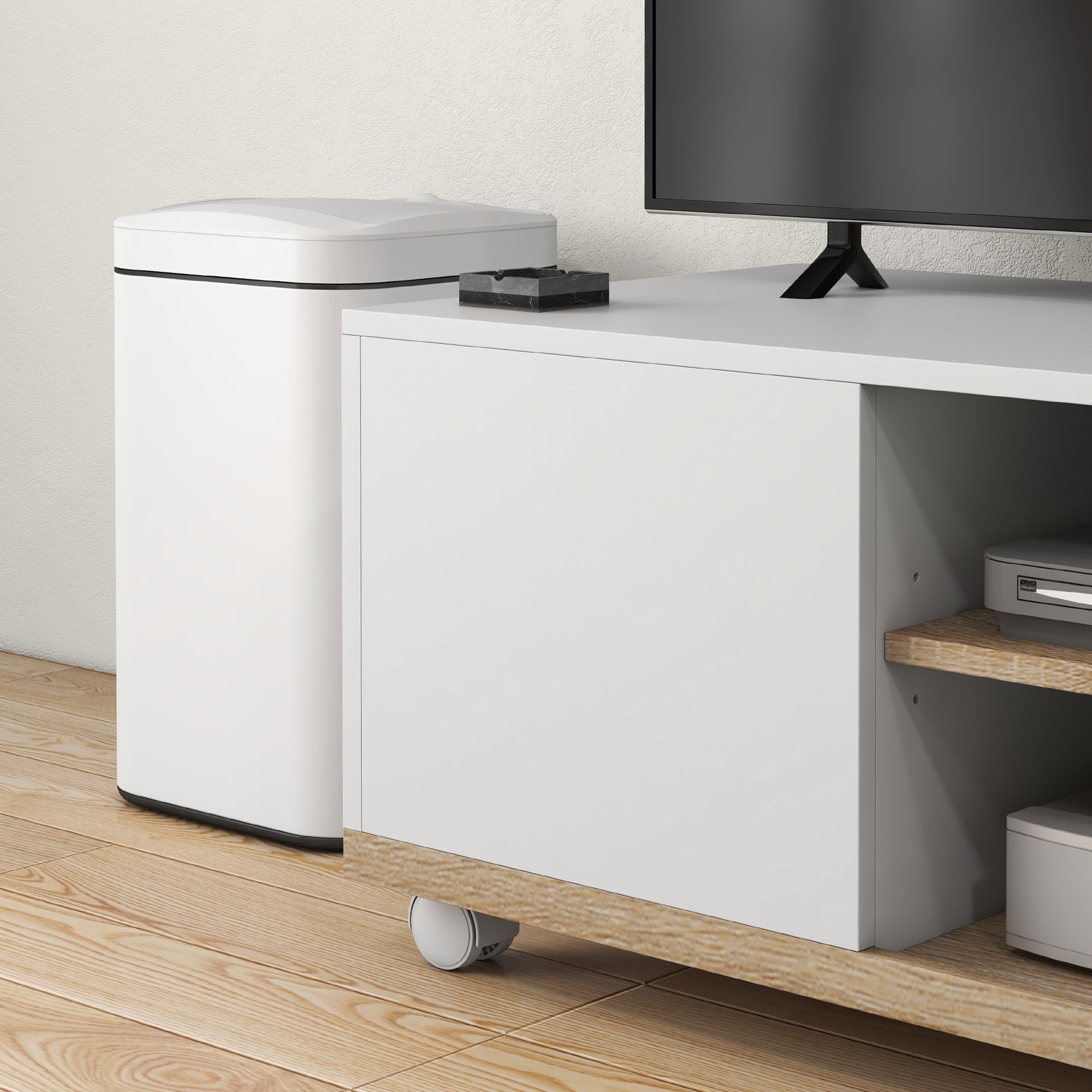 Un mobile TV bianco con una TV sopra. C'è un cestino bianco. Lo sfondo è bianco.