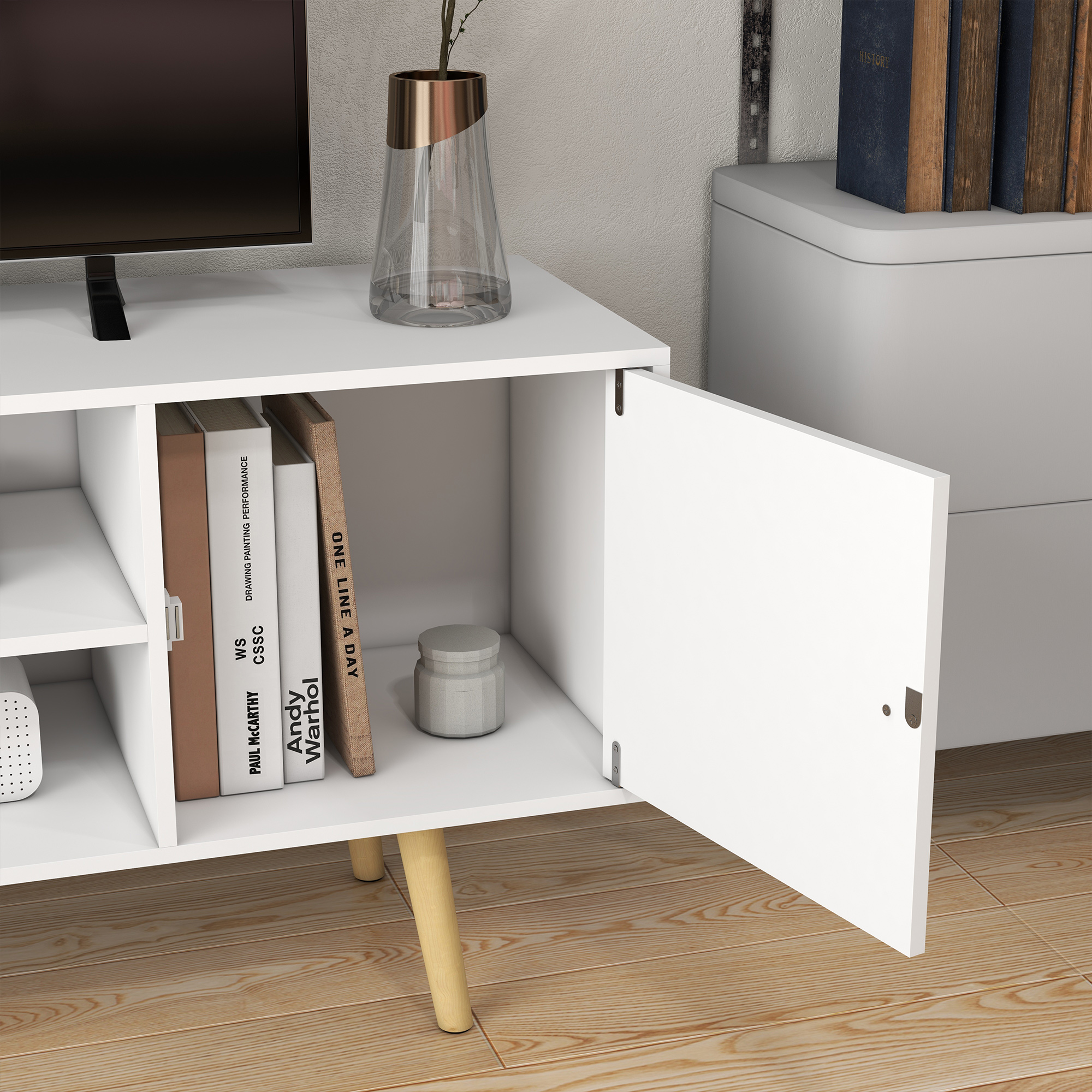 Un mobile TV bianco con ante aperte. Ci sono libri e decorazioni all'interno. Lo sfondo è bianco.