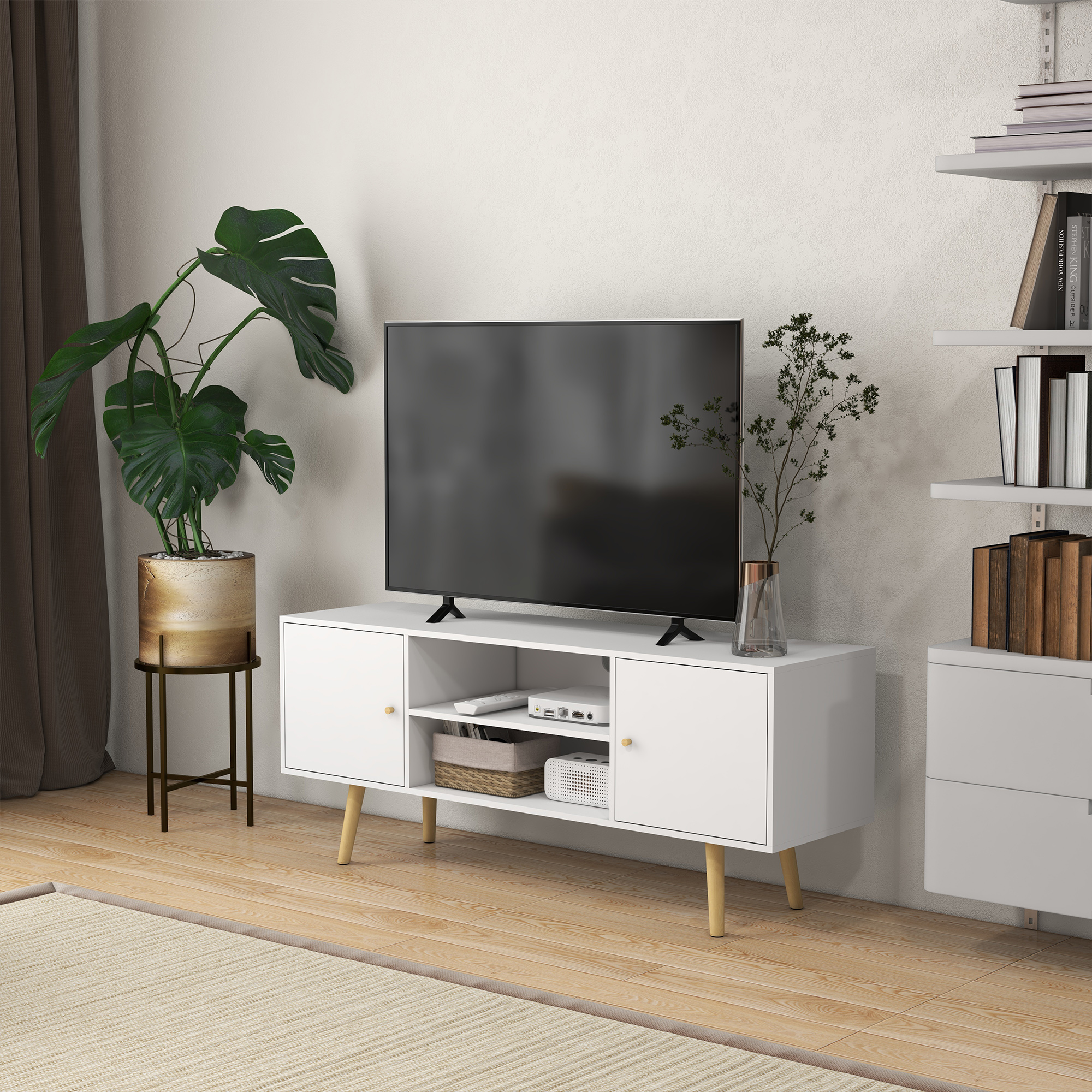 Mobile TV bianco con TV e una pianta a sinistra. Il muro ha una mensola. Un tappeto è sul pavimento.