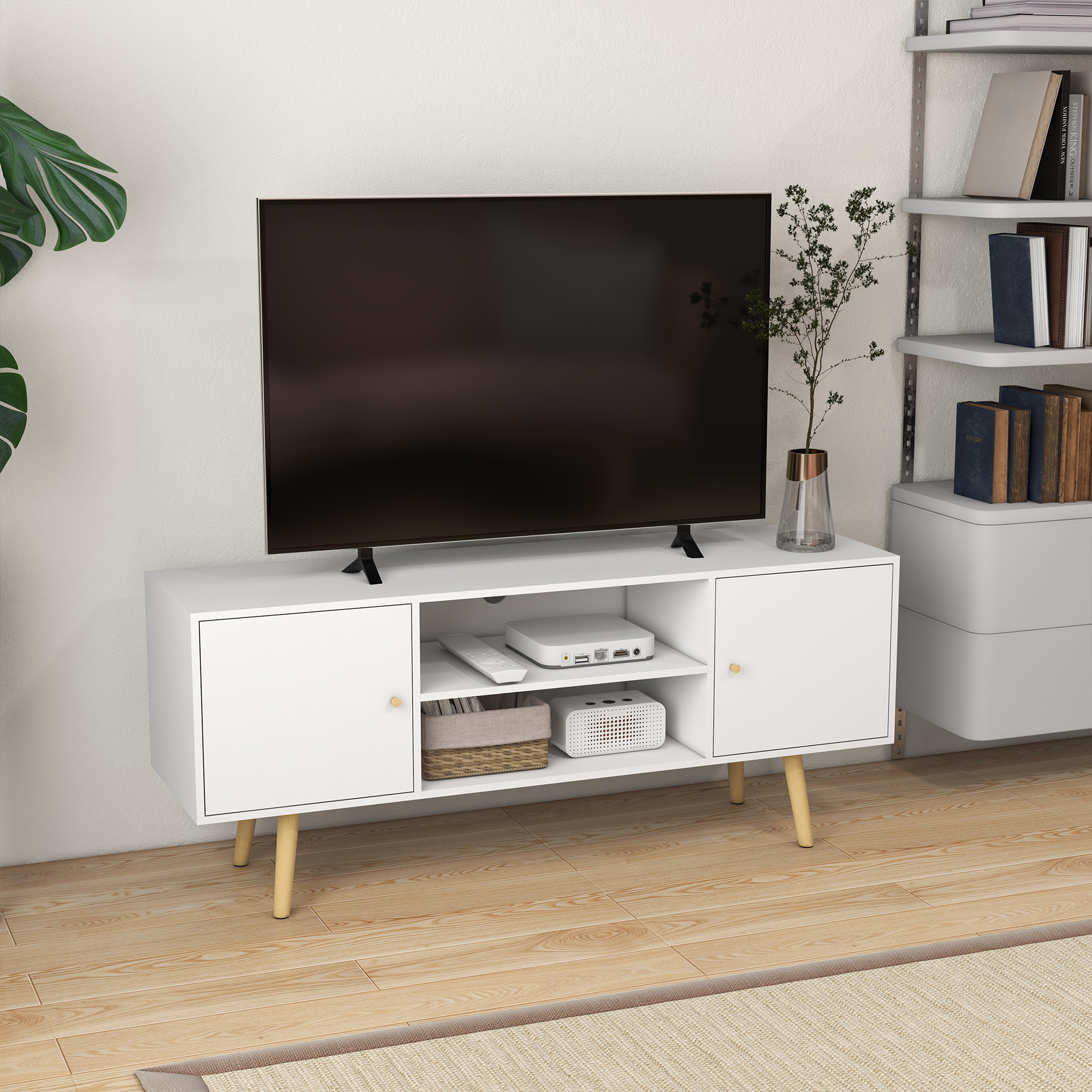 Mobile TV bianco con TV, ante e decorazioni. Ha un tappeto dai colori neutri.