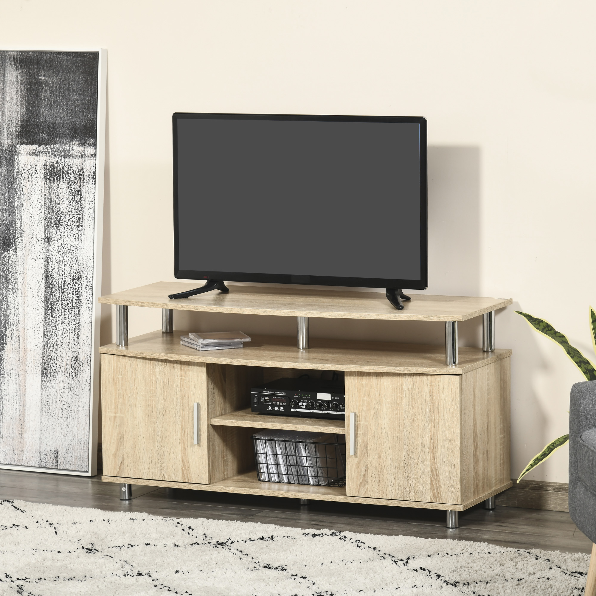 TV su un mobile in legno chiaro. Il mobile ha due armadietti e un ripiano. C'è un quadro e un tappeto.