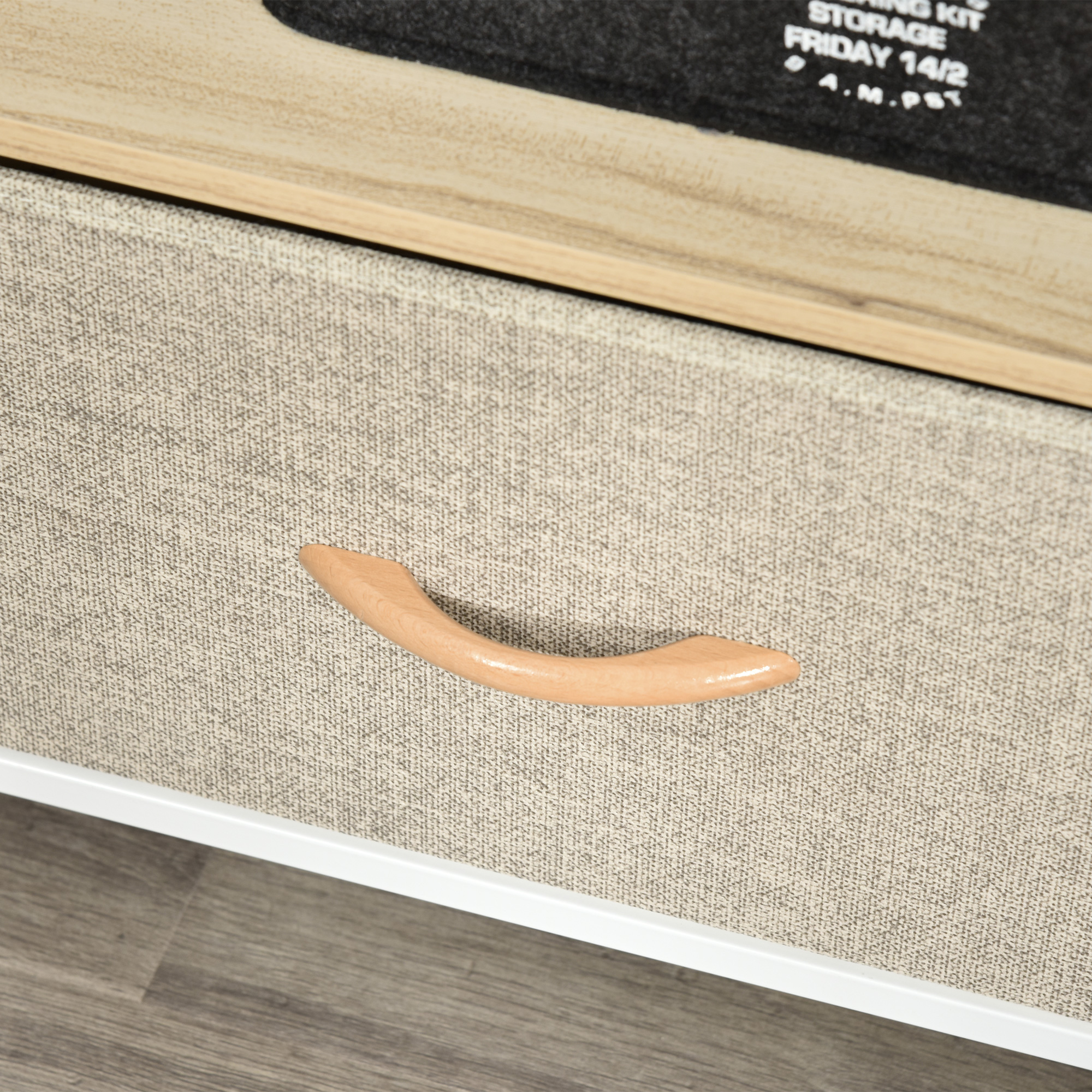 Primo piano di un cassetto con maniglia in legno chiaro. Il cassetto ha una trama in tessuto beige chiaro.