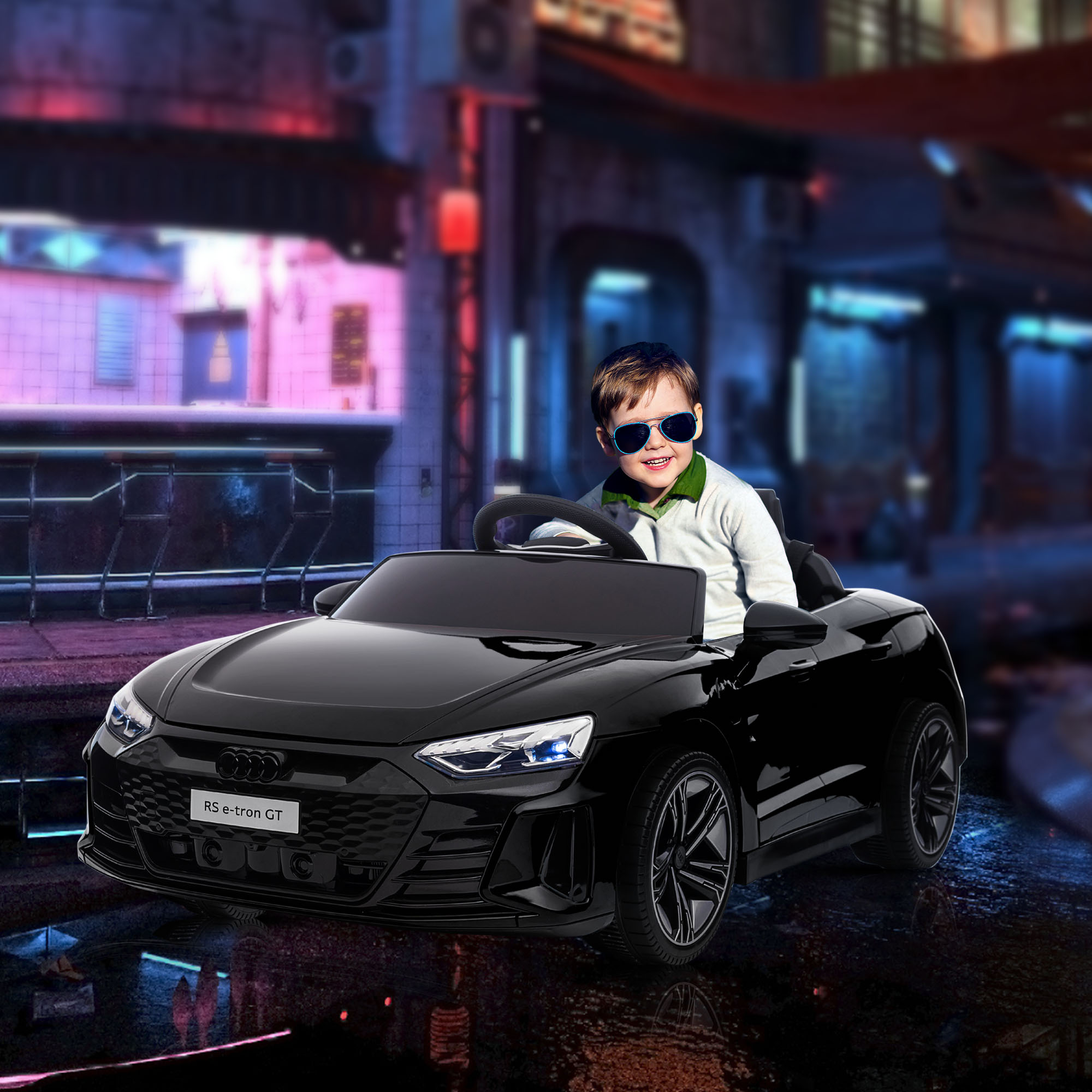 Un ragazzino con gli occhiali da sole guida un'auto giocattolo nera di notte, le luci della città sono visibili sullo sfondo.
