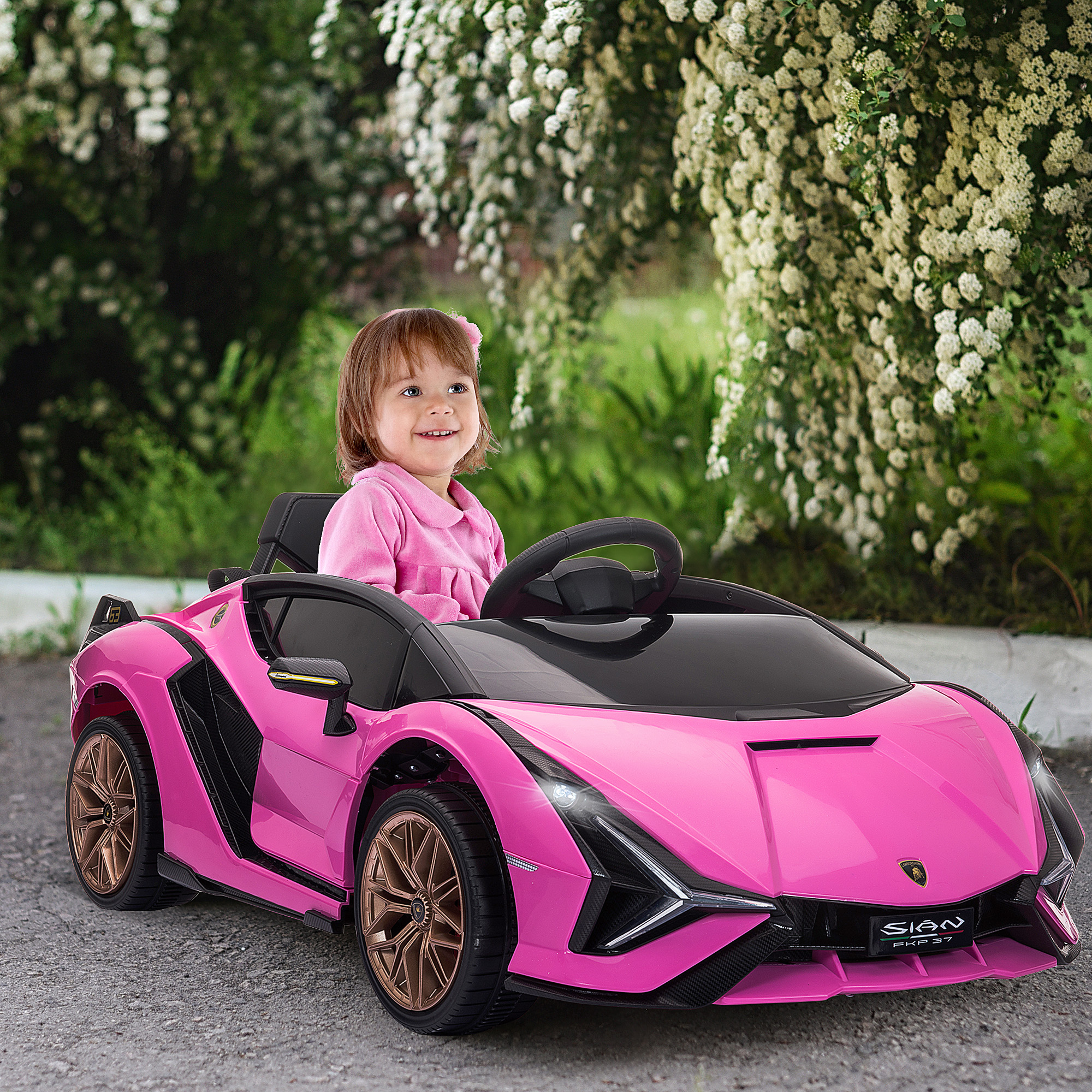 Una bambina sorridente in un'auto rosa. Auto rosa con ruote dorate. Sfondo verde con fiori bianchi.
