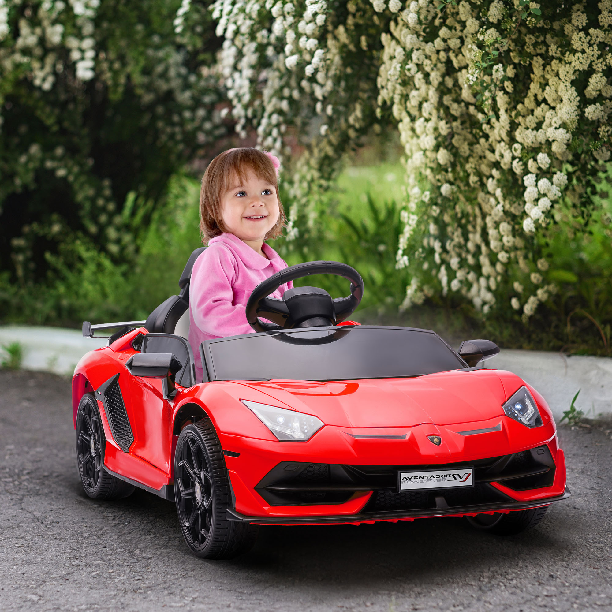 Una bambina in un'auto giocattolo rossa.