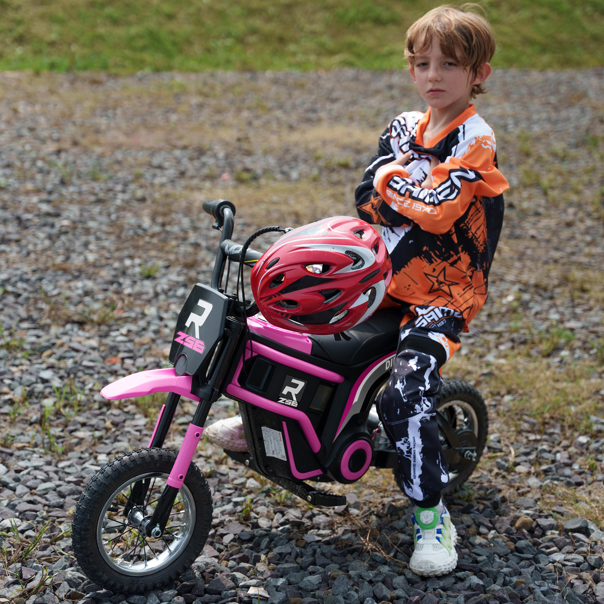 Un ragazzo seduto su una moto giocattolo rosa.