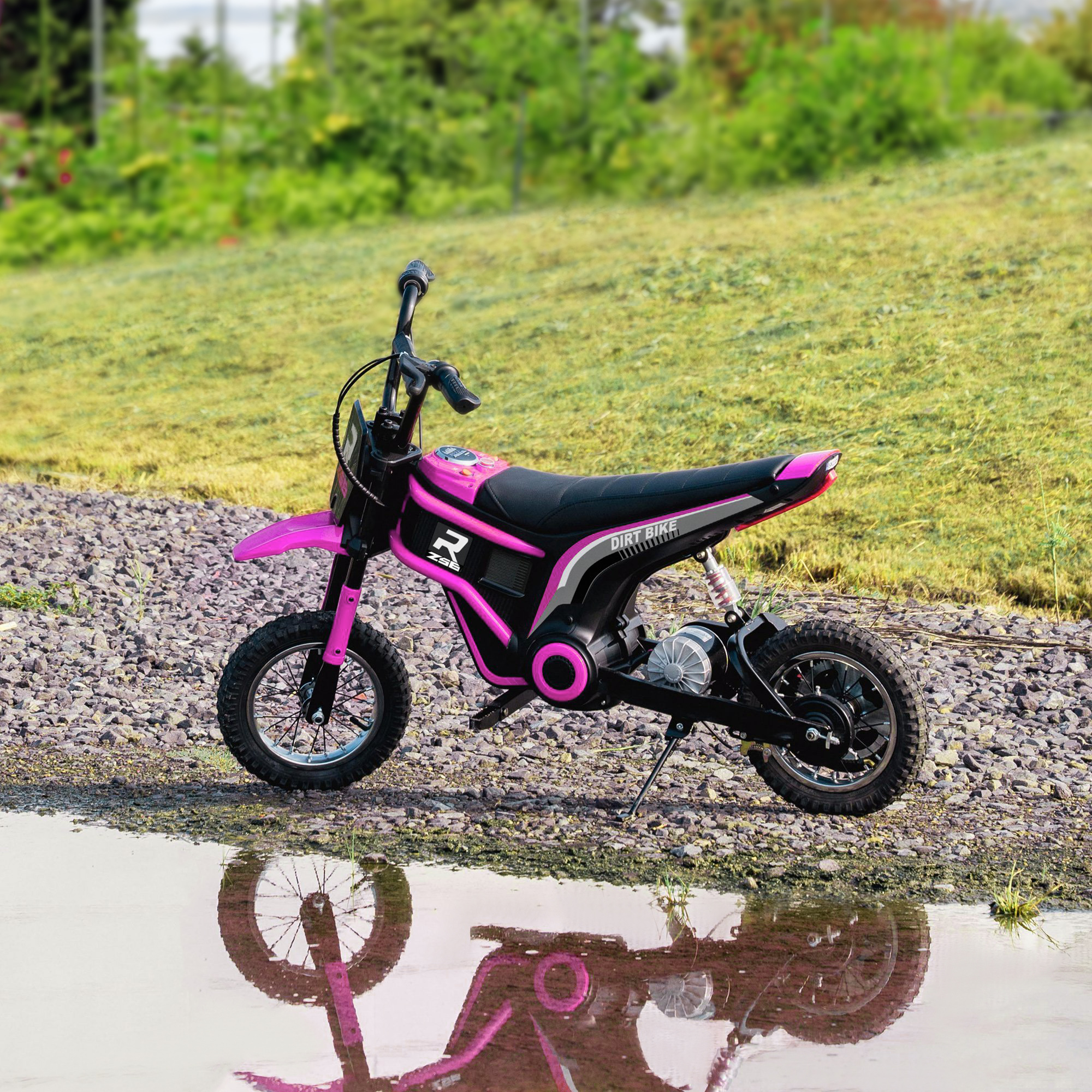 Moto da cross giocattolo rosa su una superficie bagnata. Riflesso nell'acqua. Erba verde sullo sfondo.