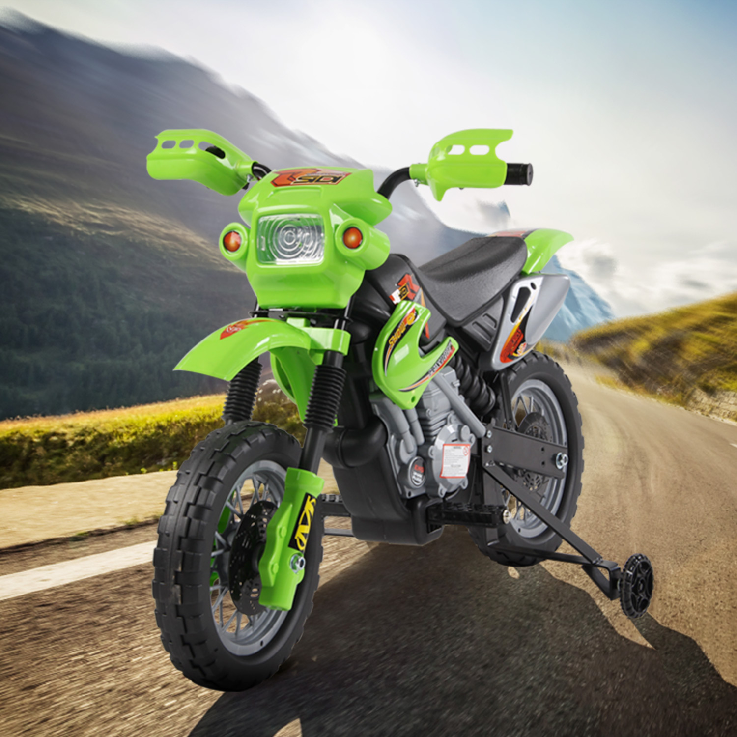 Una moto giocattolo verde con rotelle su una strada con sfondo montuoso.
