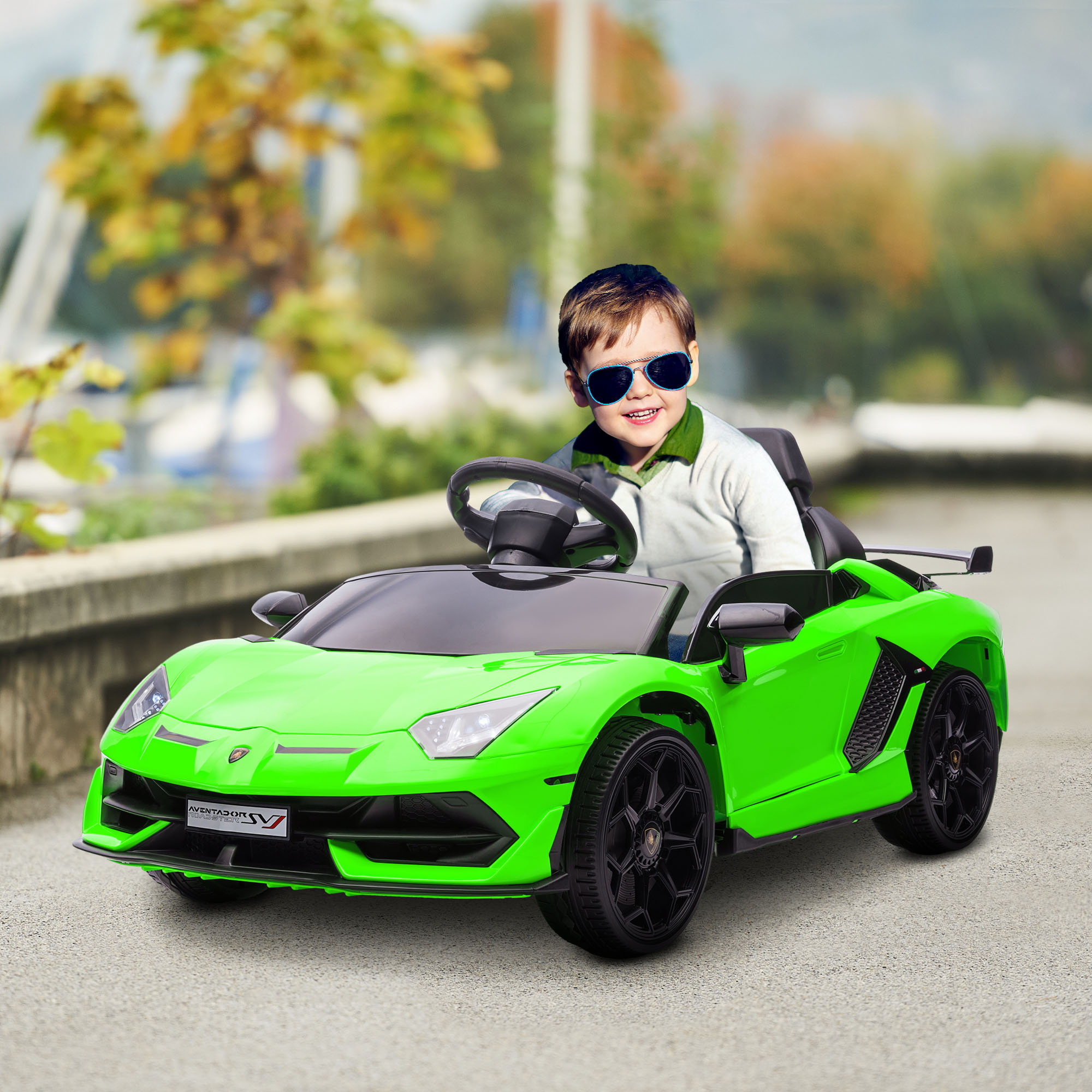 Un ragazzo con gli occhiali da sole è seduto in un'auto giocattolo verde. L'auto è su una strada.