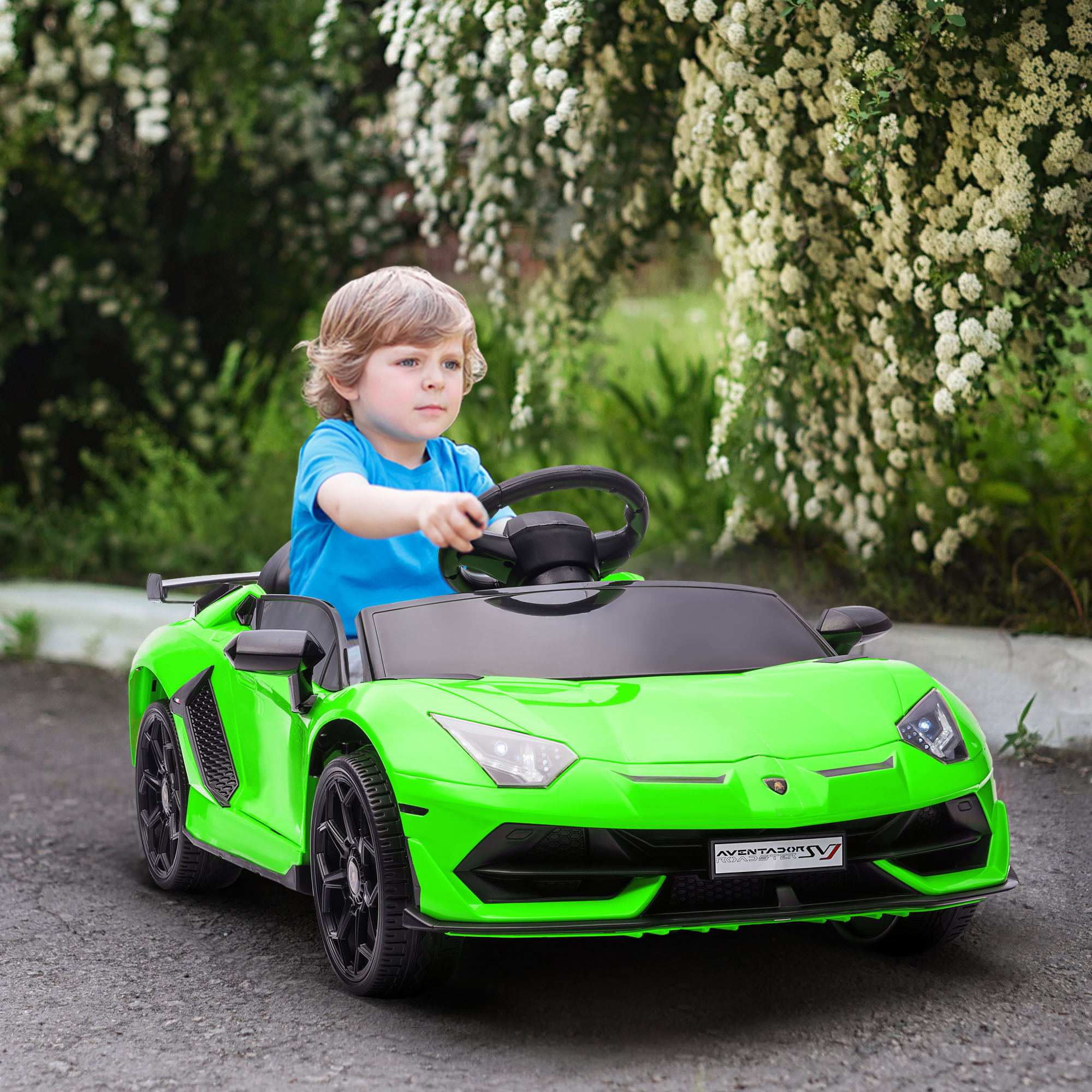 Un bambino guida un'auto giocattolo Lamborghini verde su una strada asfaltata. Arbusti verdi sullo sfondo.