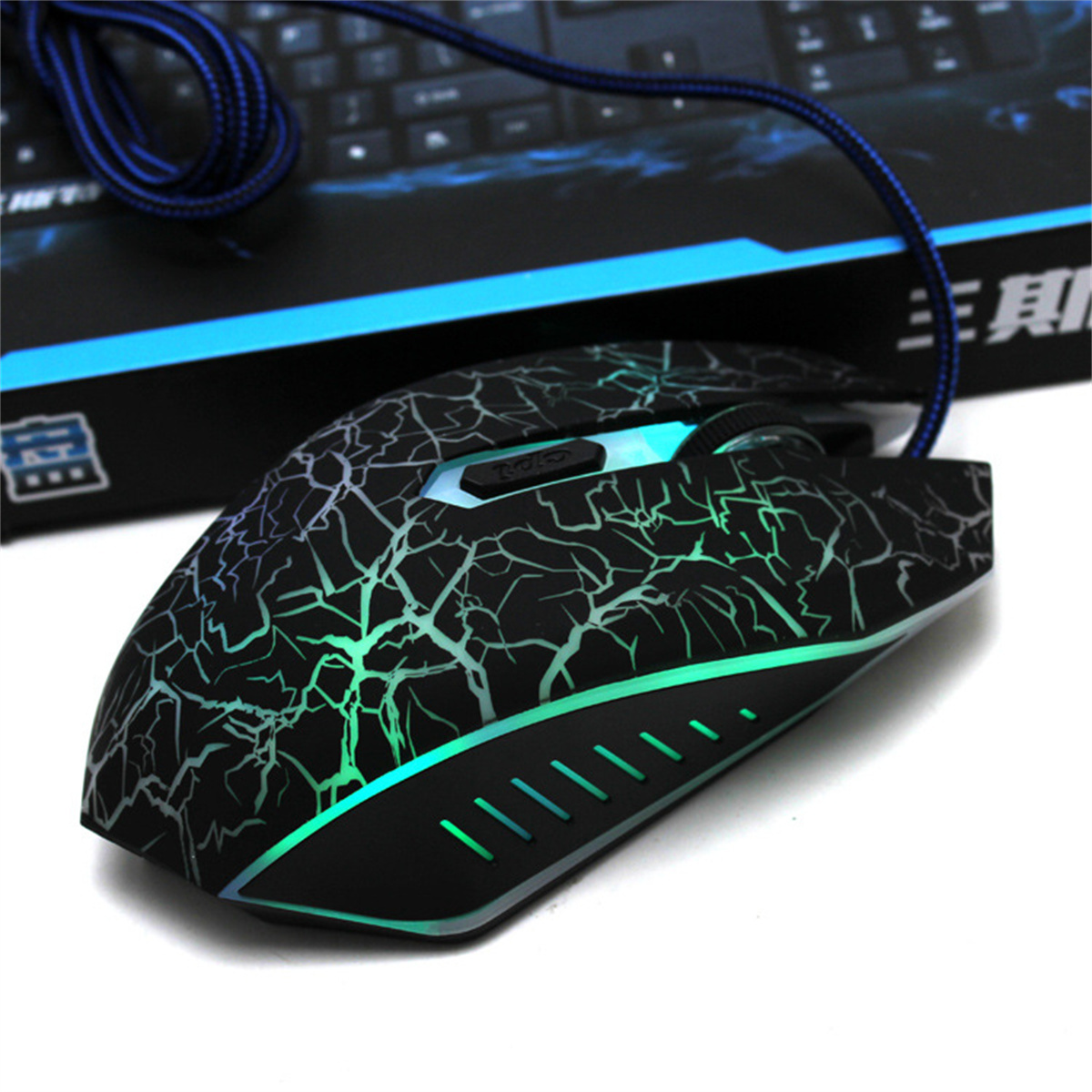Schwarze Gaming-Maus mit rissigem Design und blauem Kabel. Die Maus hat grüne Lichter.